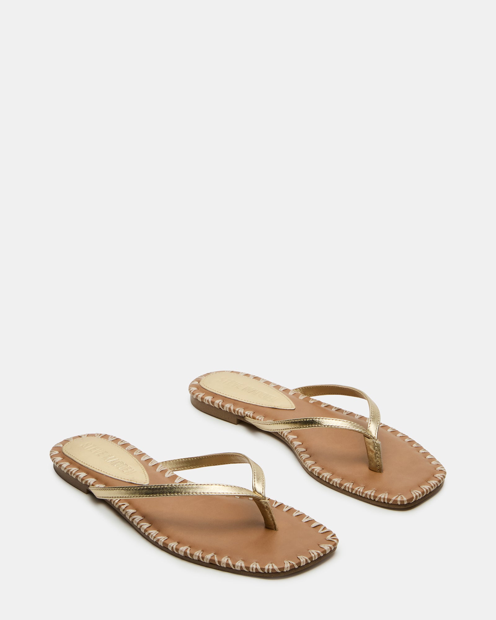 Close-up of gold flat sandals showing textured leather finish