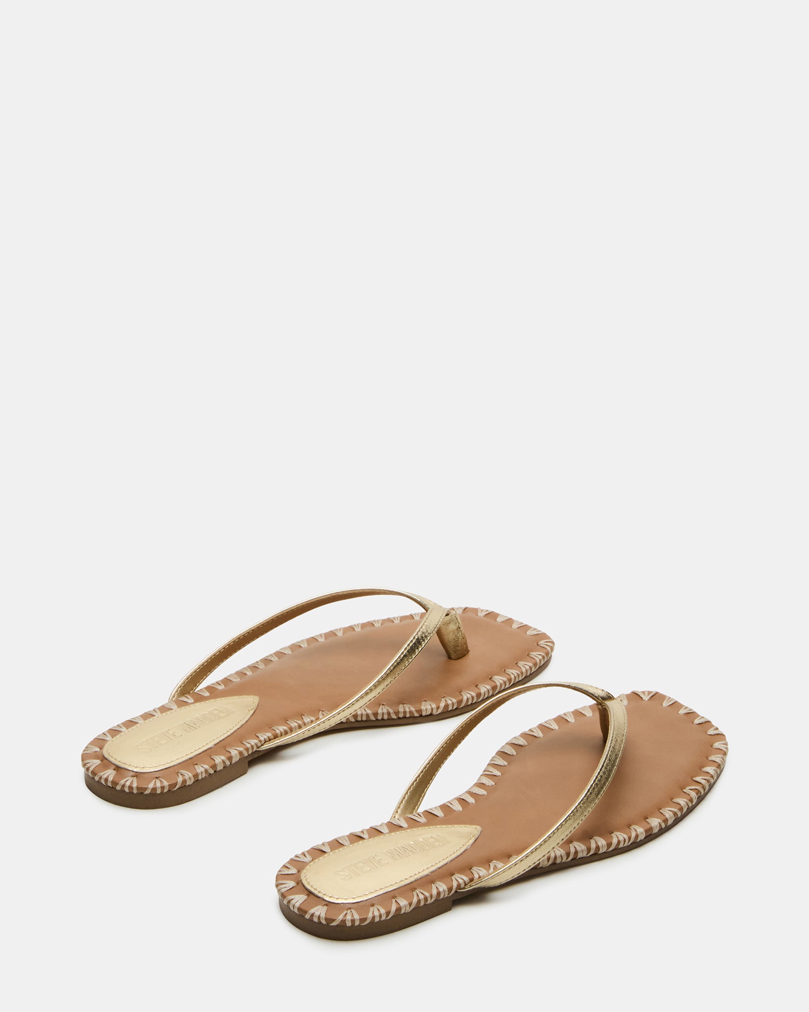 Close-up of gold flat sandals showing textured leather finish