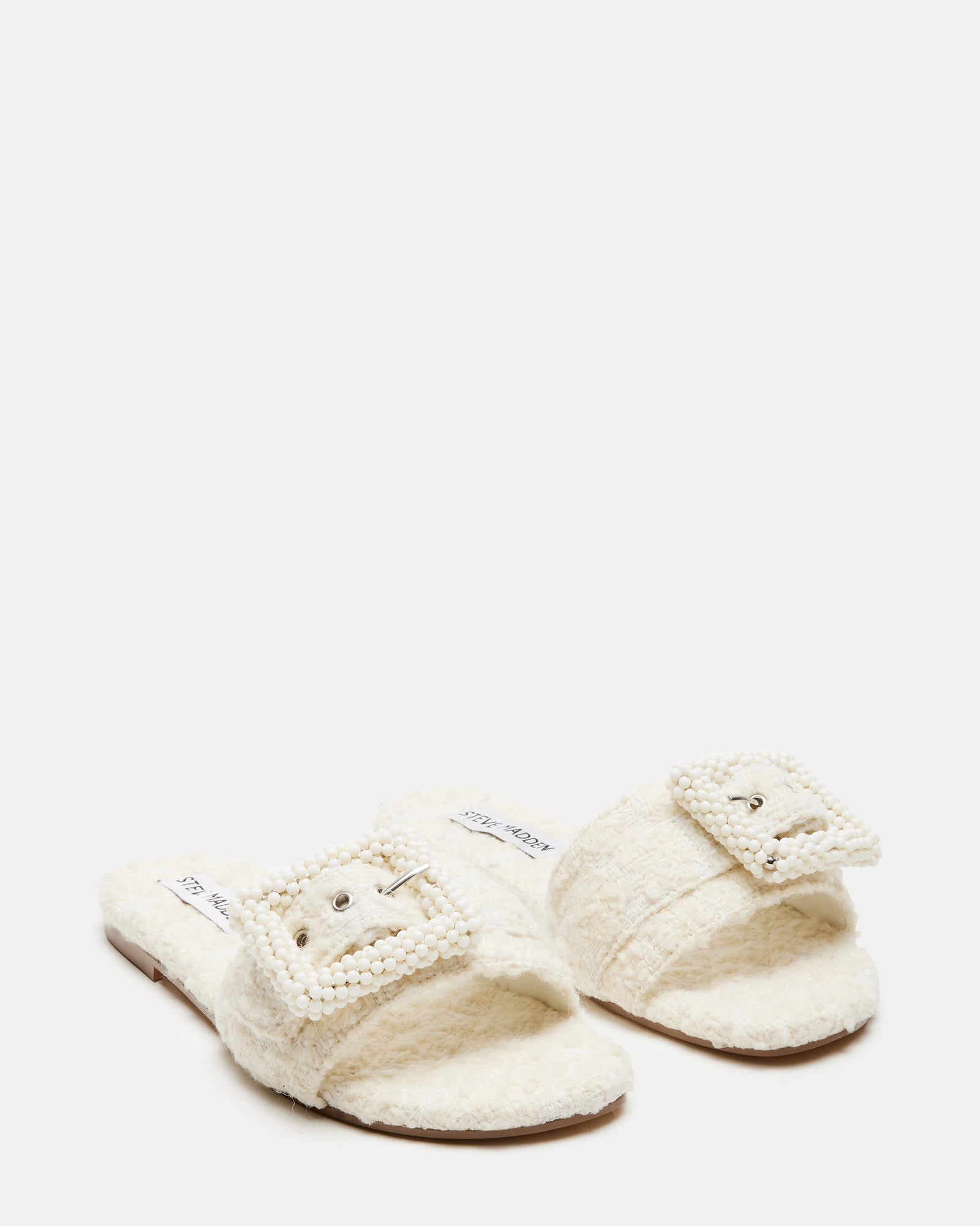 Side angle of flat sandal showing low heel and pearl-textured strap detail.