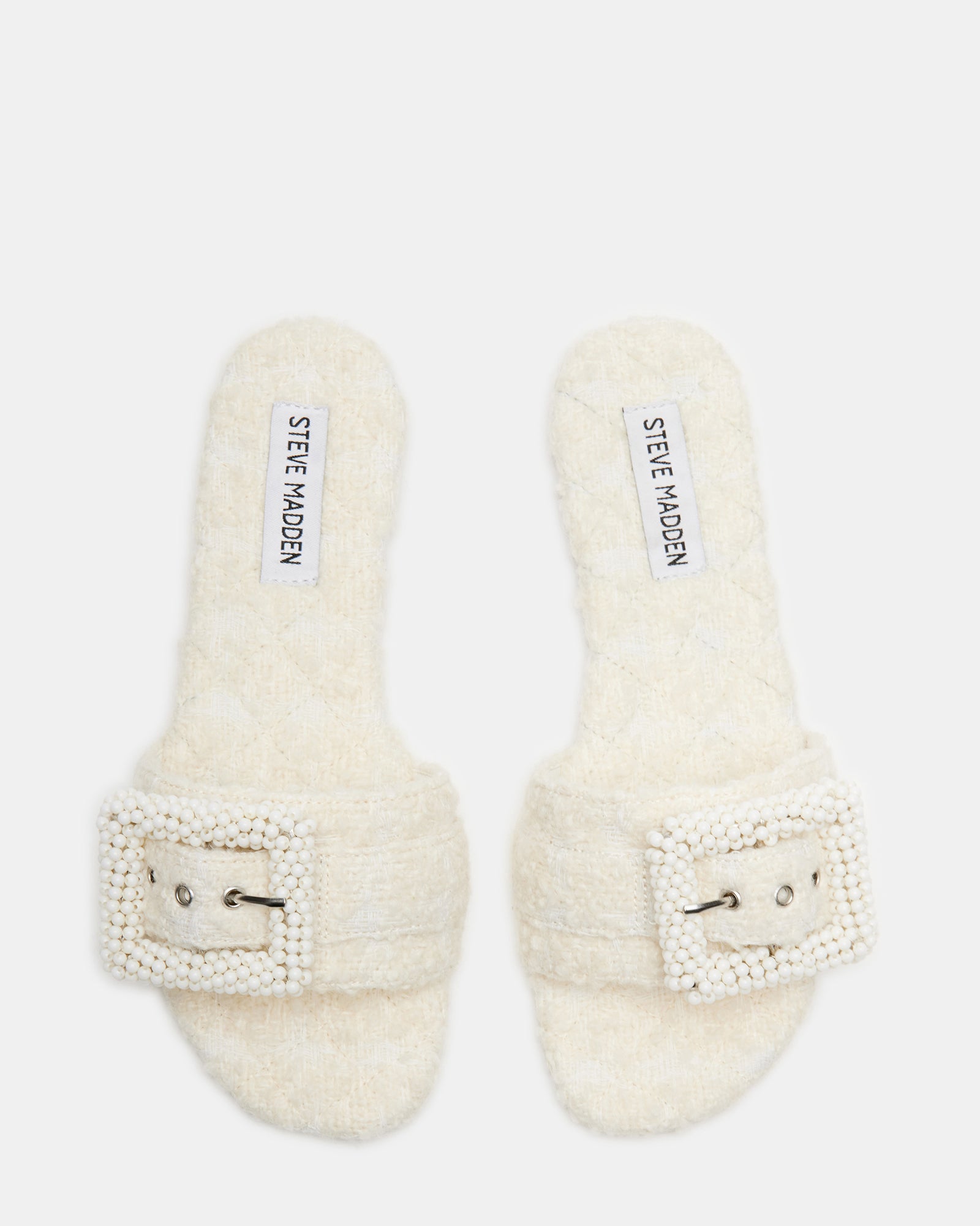 Top-down view of Marika ivory slide sandal with rhinestone buckle on neutral surface.