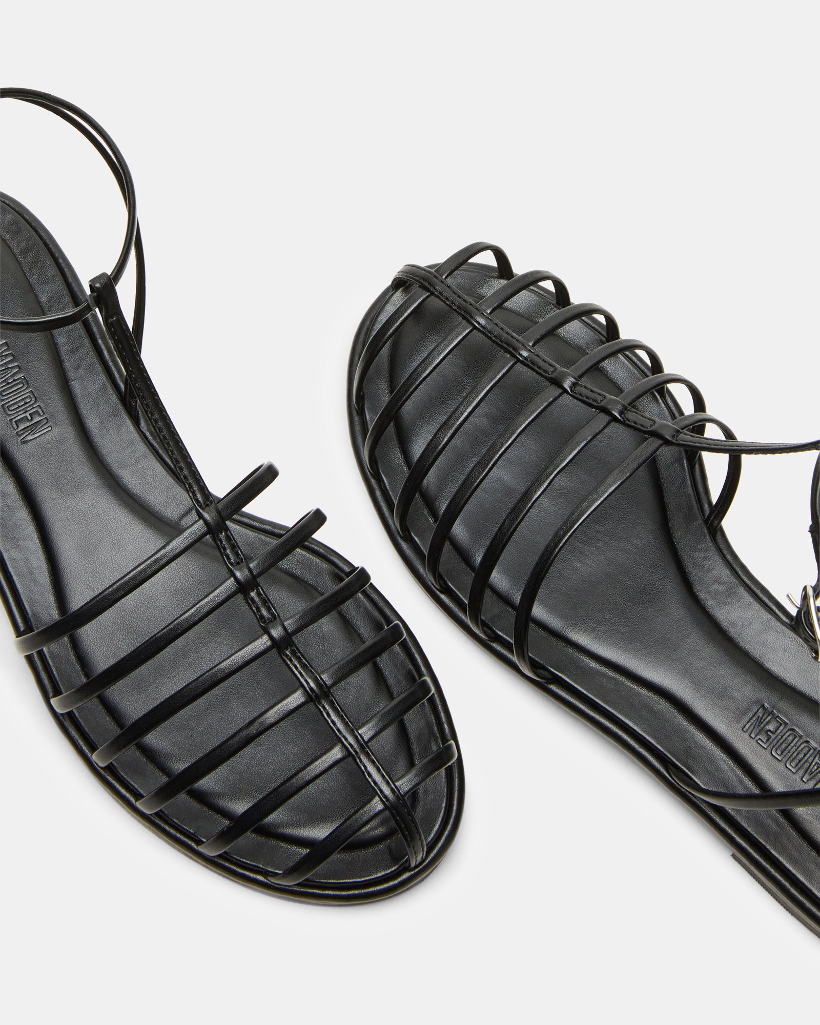 Side view of Marin Black womens fisherman sandals on a sandy beach.