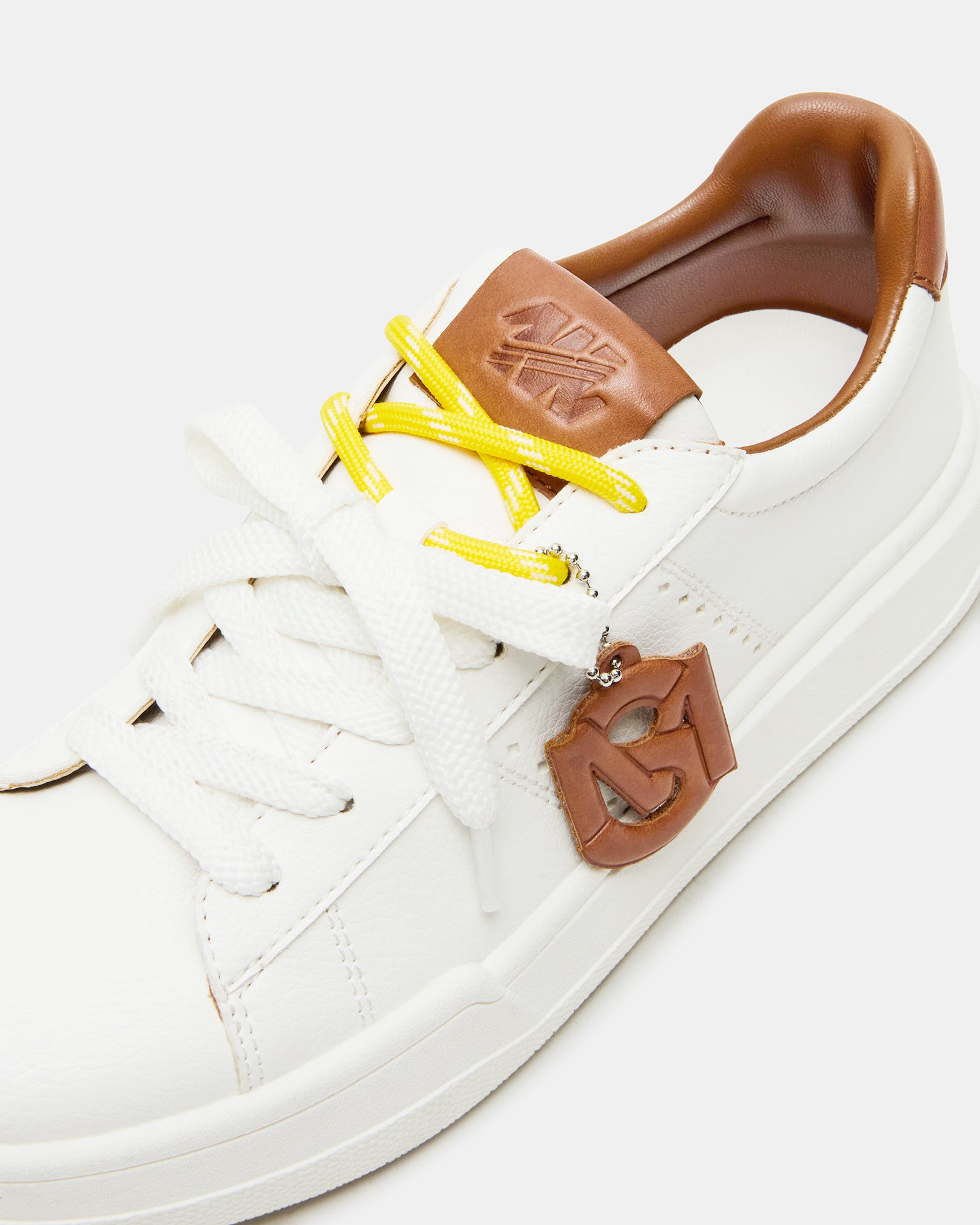 Side profile of white and tan lace up sneakers with decorative charm—ideal for city walks.