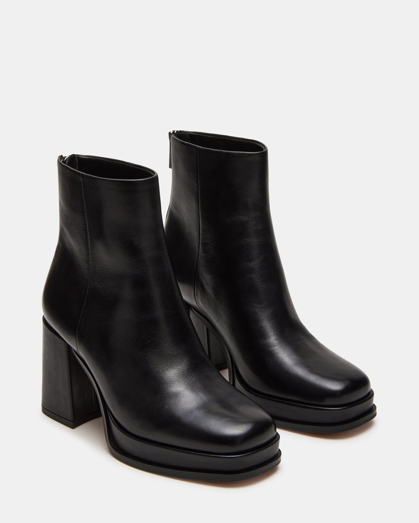 Close-up of black leather boots texture and stitching details on city pavement