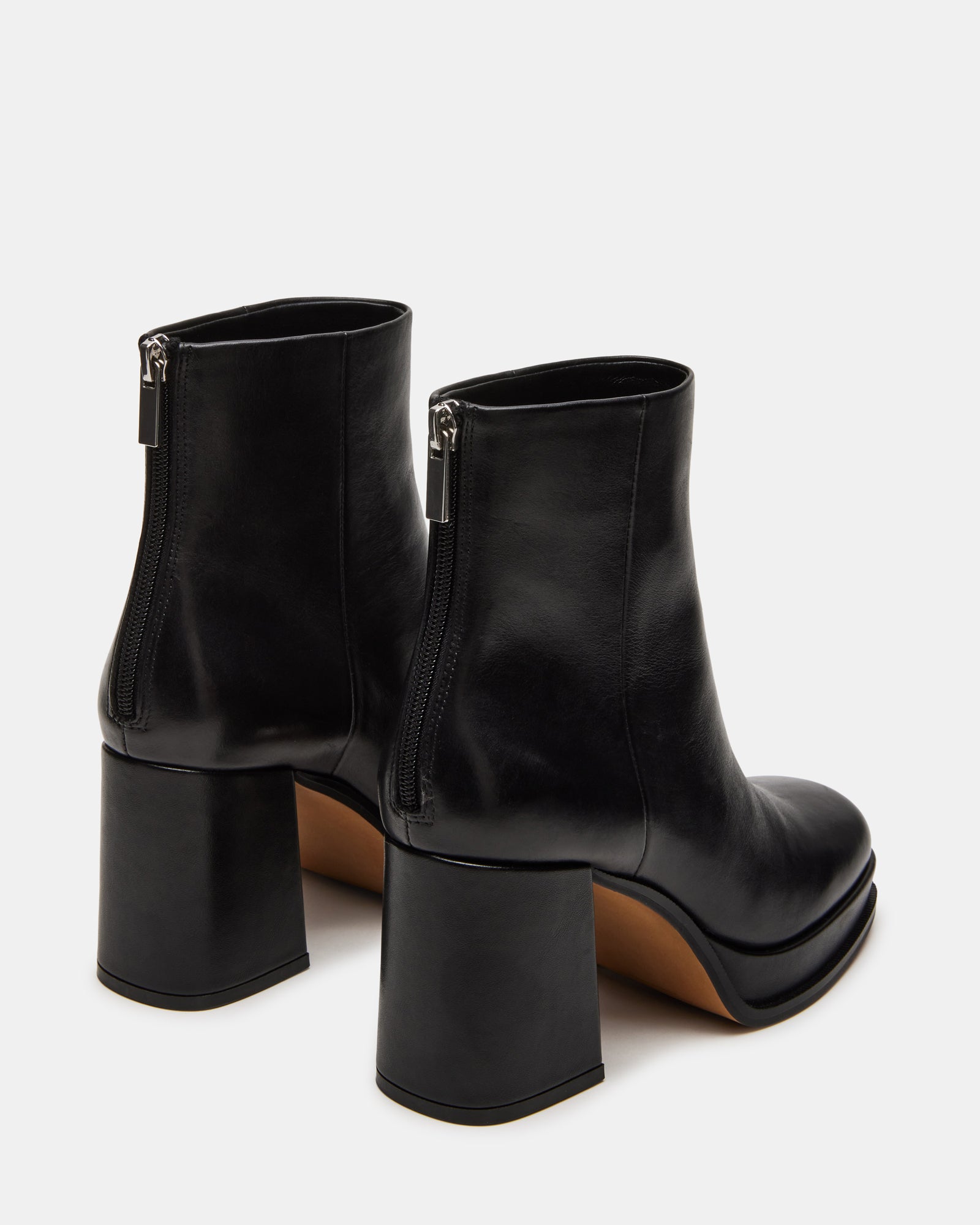 Close-up of black leather boots texture and stitching details on city pavement