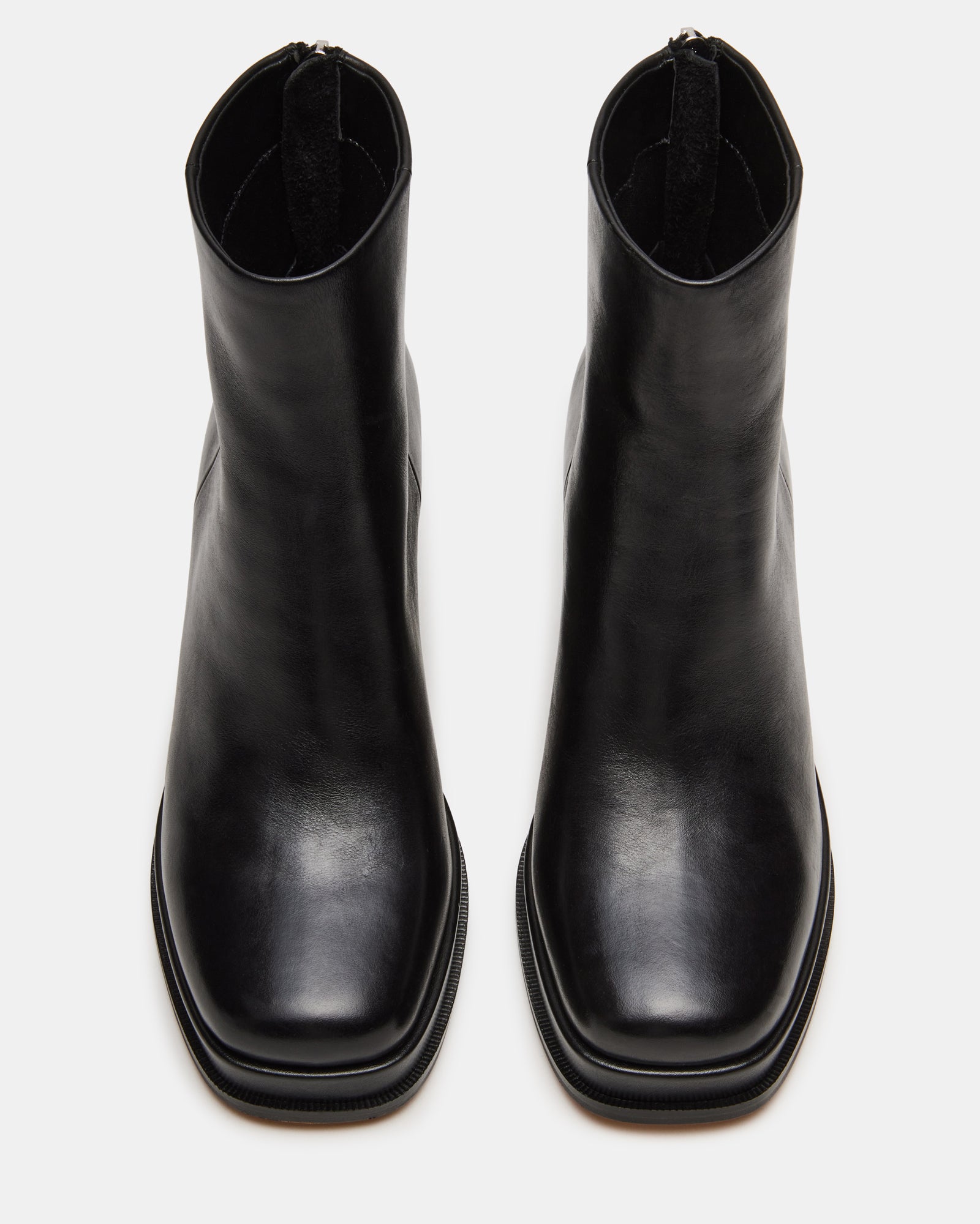 Pair of brown leather boots and black ankle boots styled next to weekend travel essentials