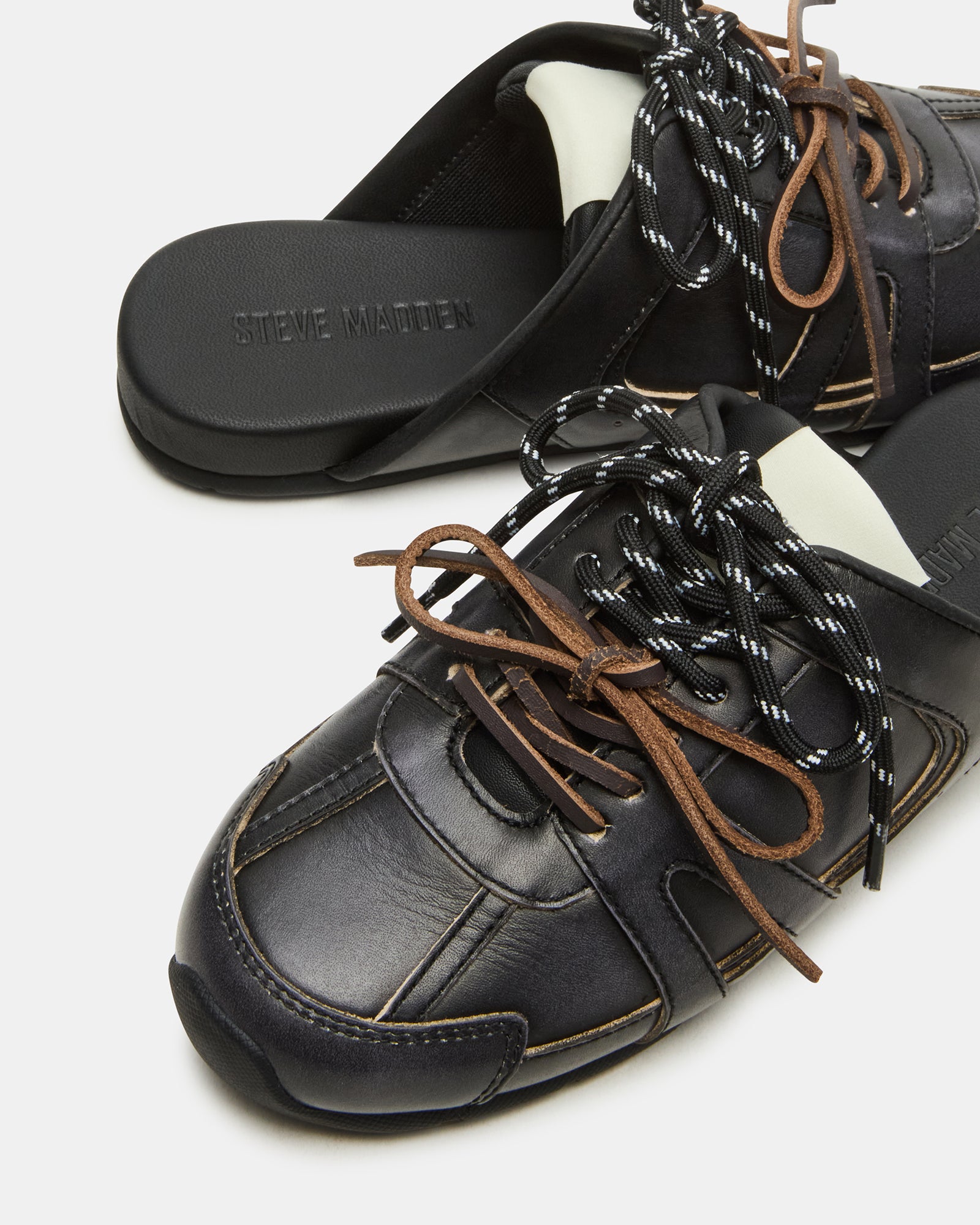 Side view of distressed lace-up mule sneakers in black leather for casual outings
