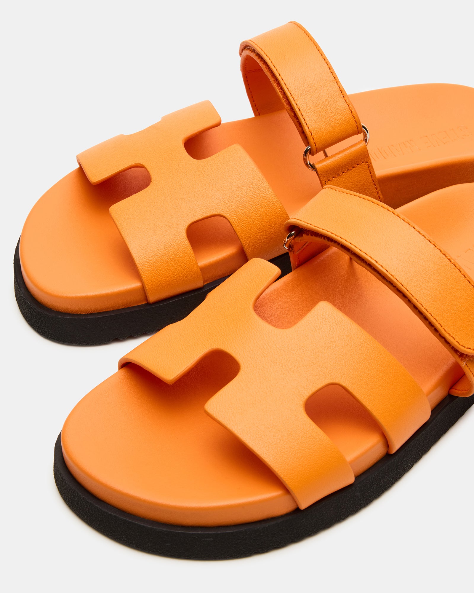 Side view of orange leather slides with geometric cutout design and platform sole