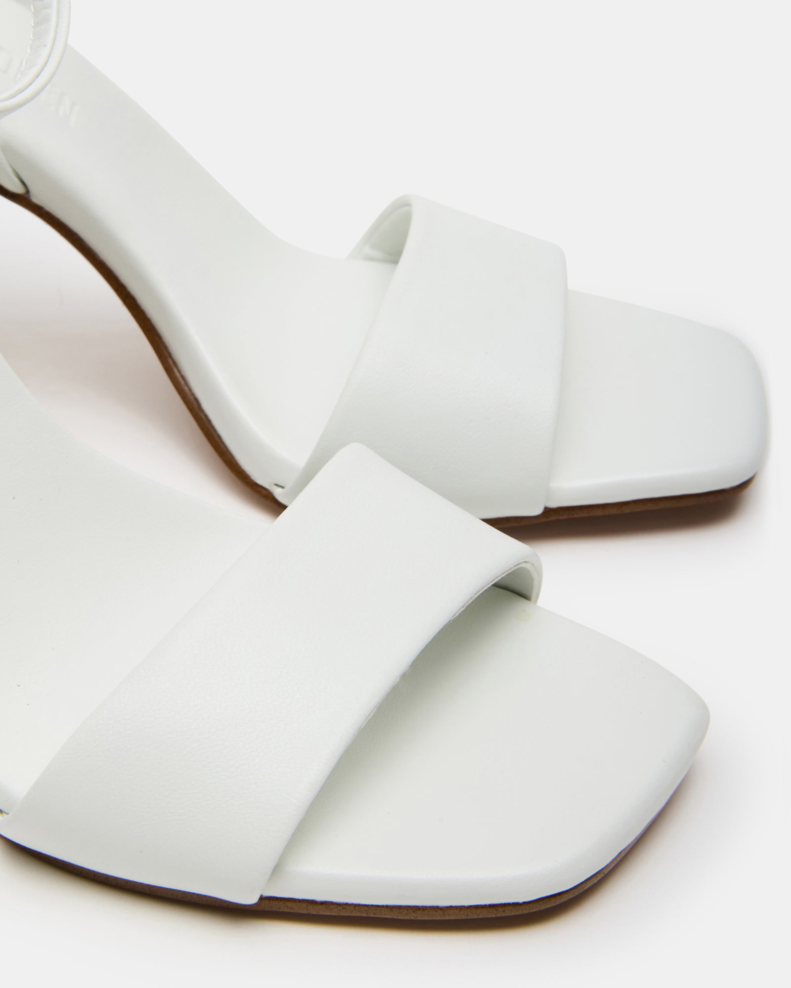 Model wearing white heels with a sturdy block heel and ankle strap