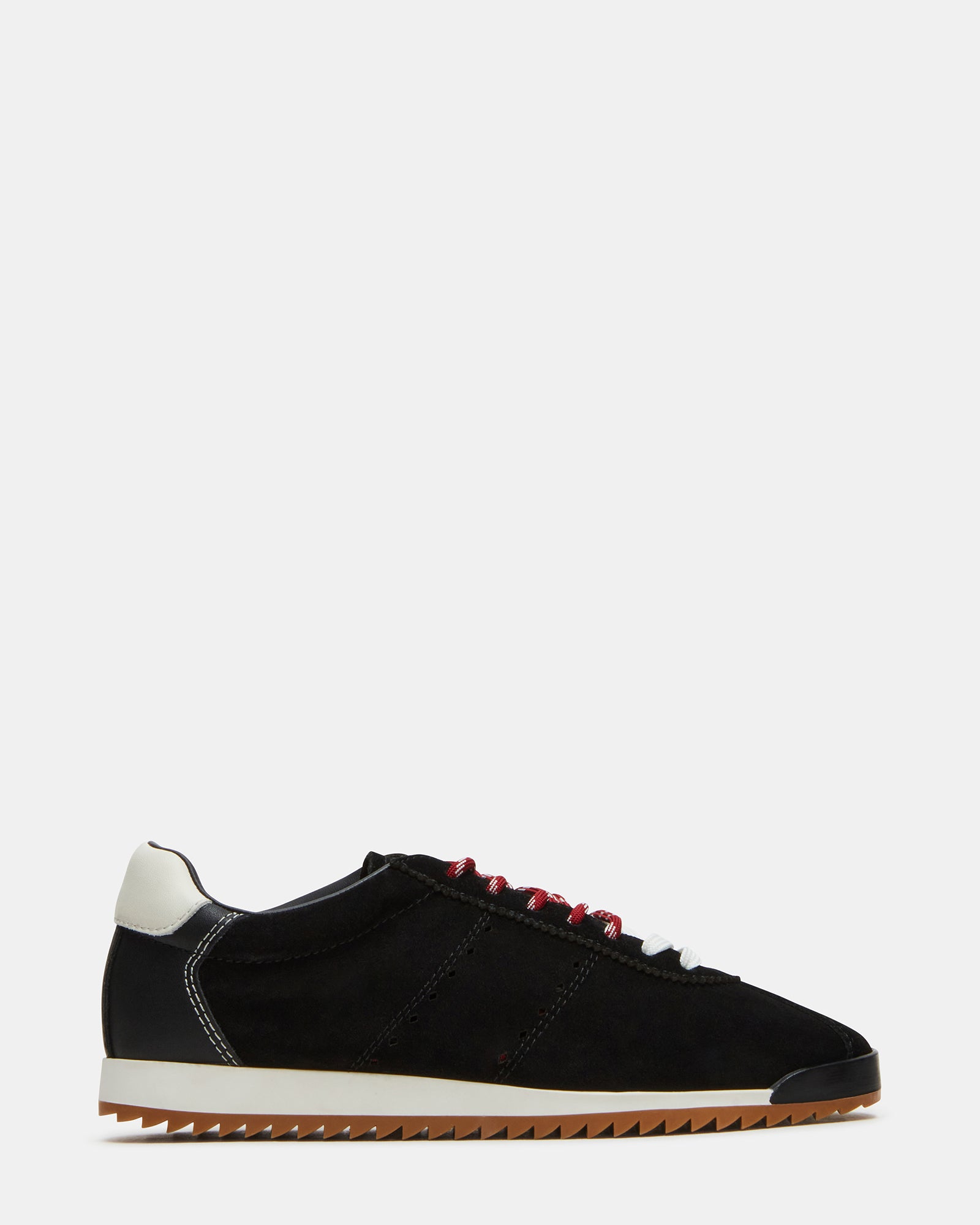 Black suede sneakers on a wooden floor, showcasing the low-top design