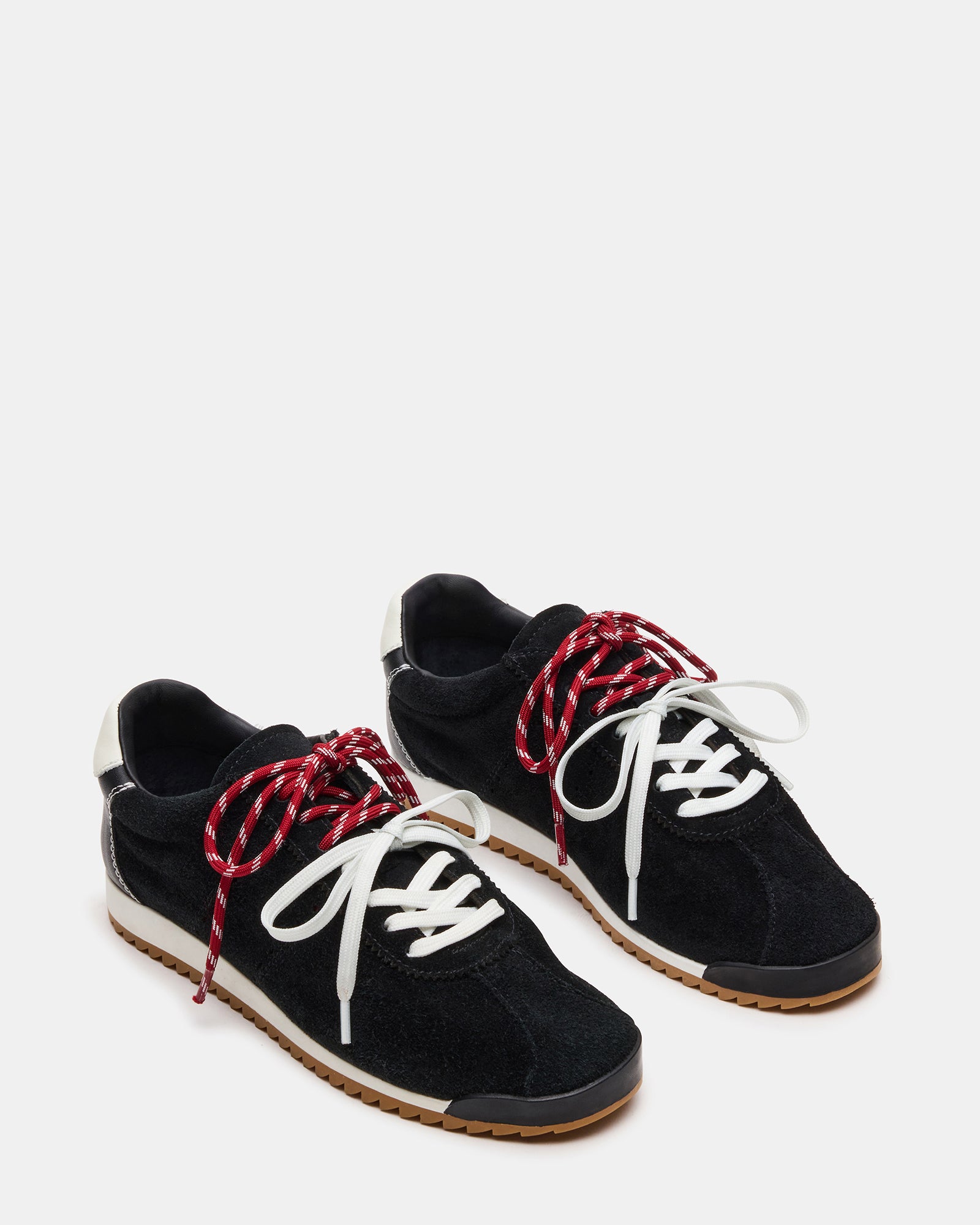 Black suede sneakers on a wooden floor, showcasing the low-top design