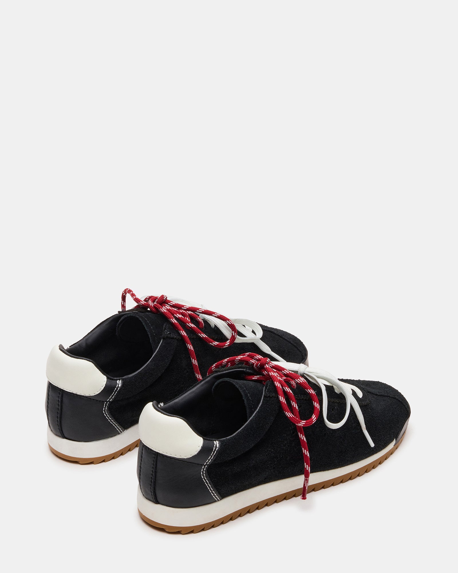 Black suede sneakers on a wooden floor, showcasing the low-top design
