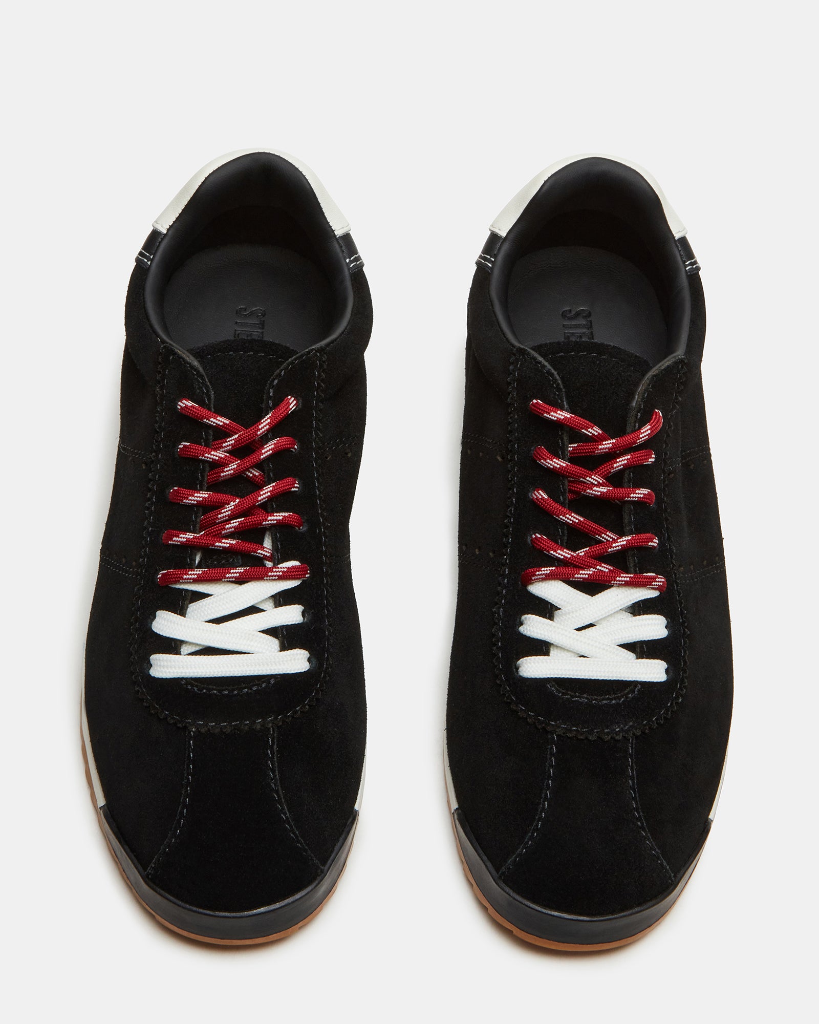 Black suede sneakers on a wooden floor, showcasing the low-top design