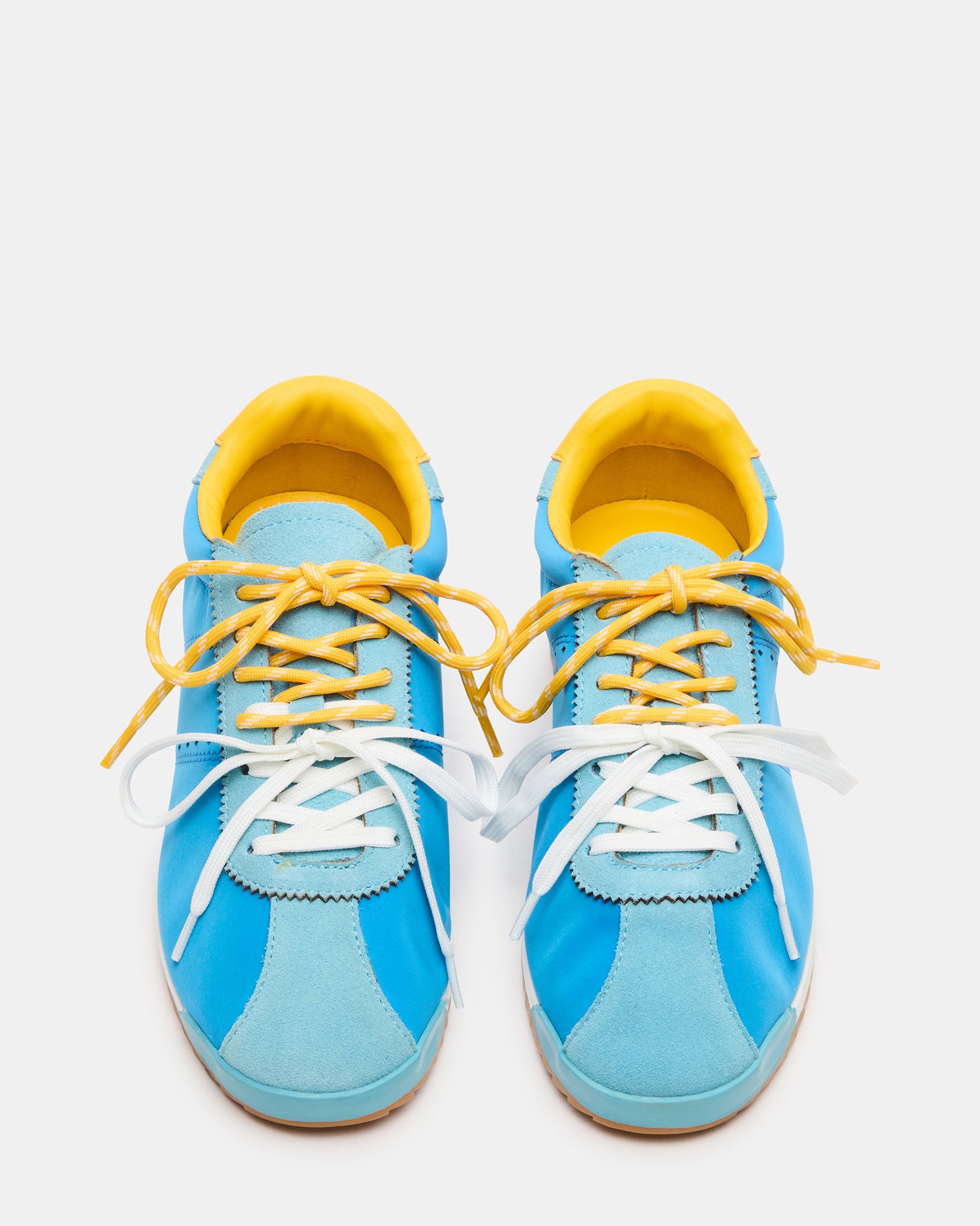 Side view of white sneakers with blue/yellow accents, styled with jeans