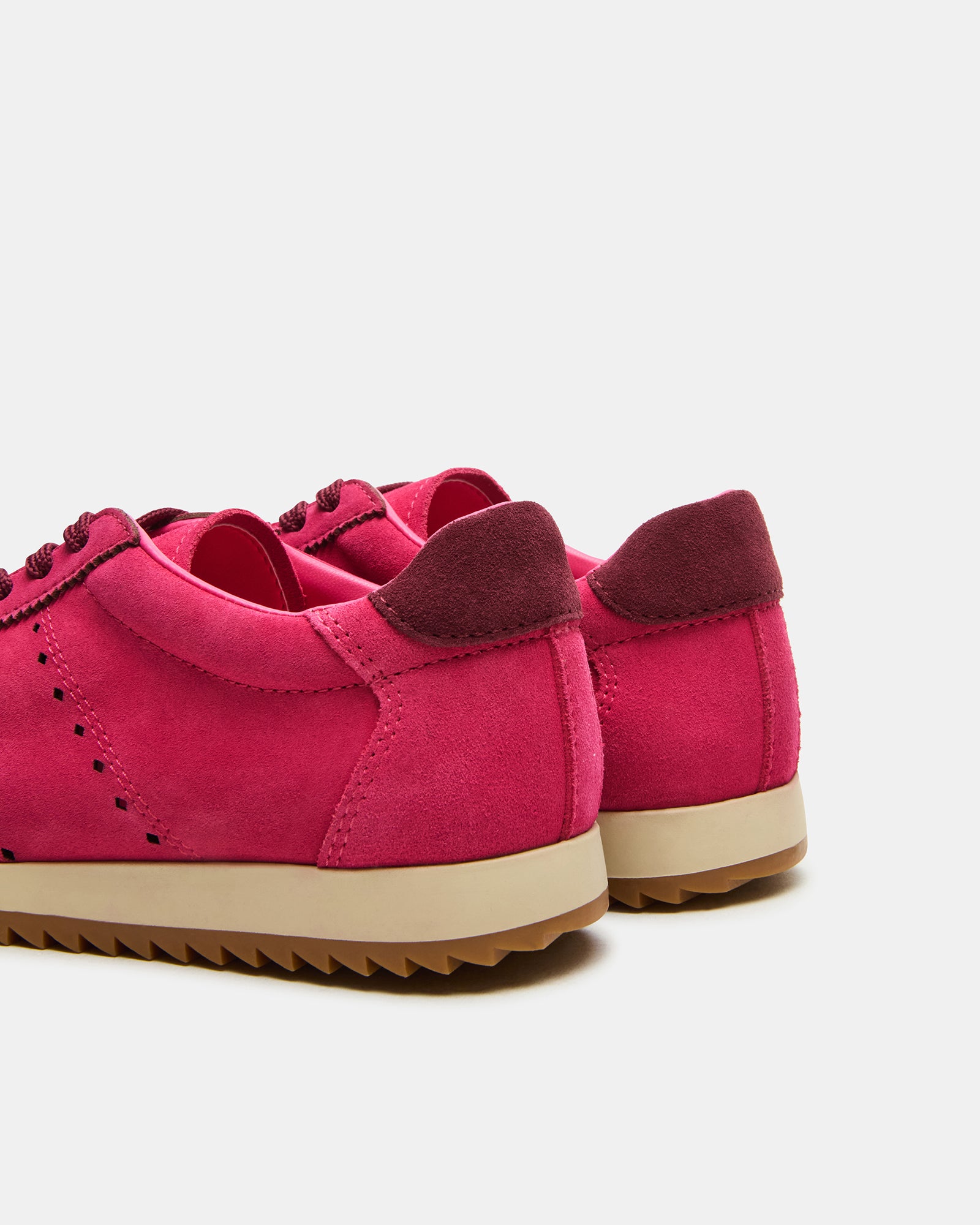 Side view of hot pink womens lace-up sneakers on a sidewalk.