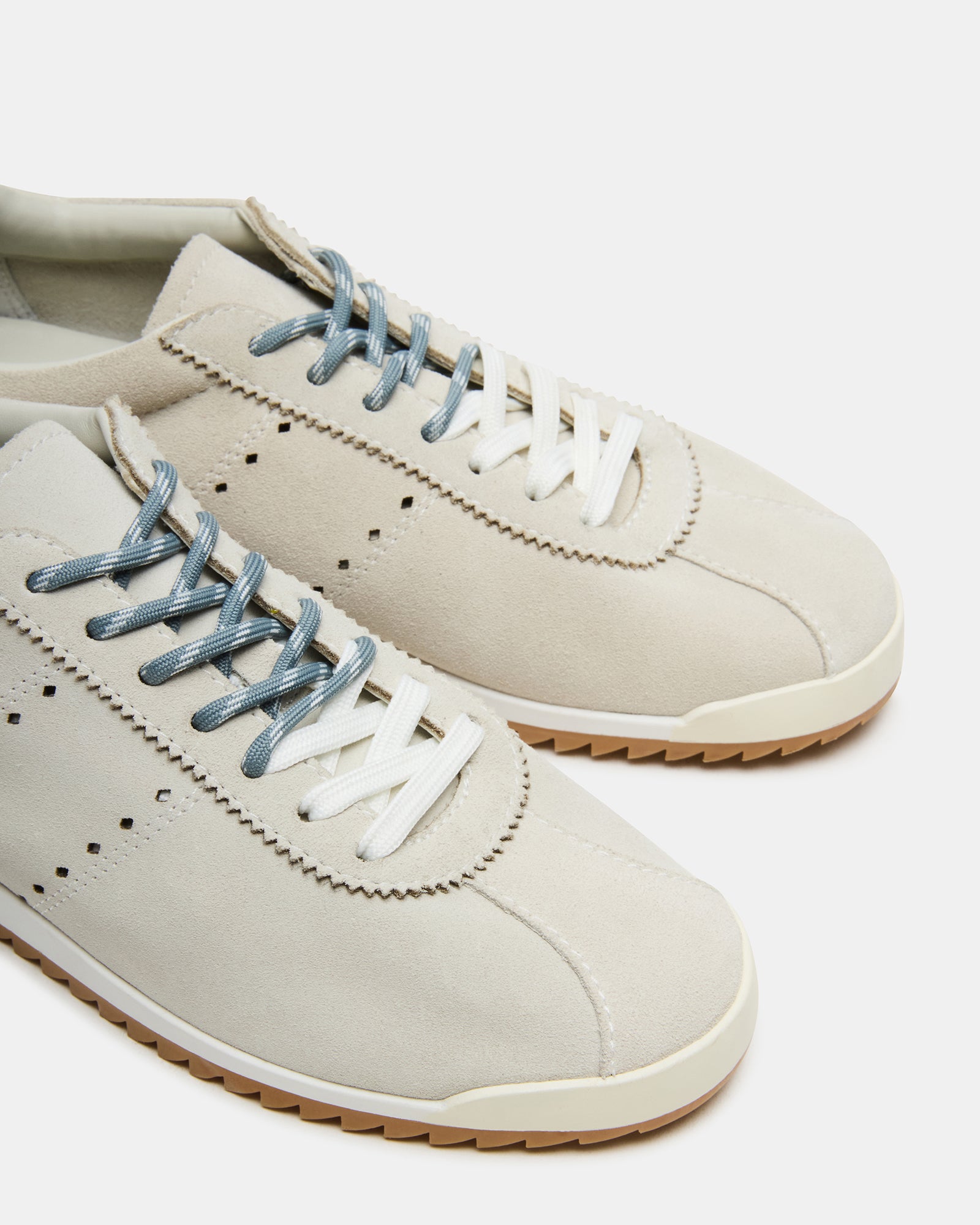 Top angle of lace-up sneakers showing dual lace colors and suede texture