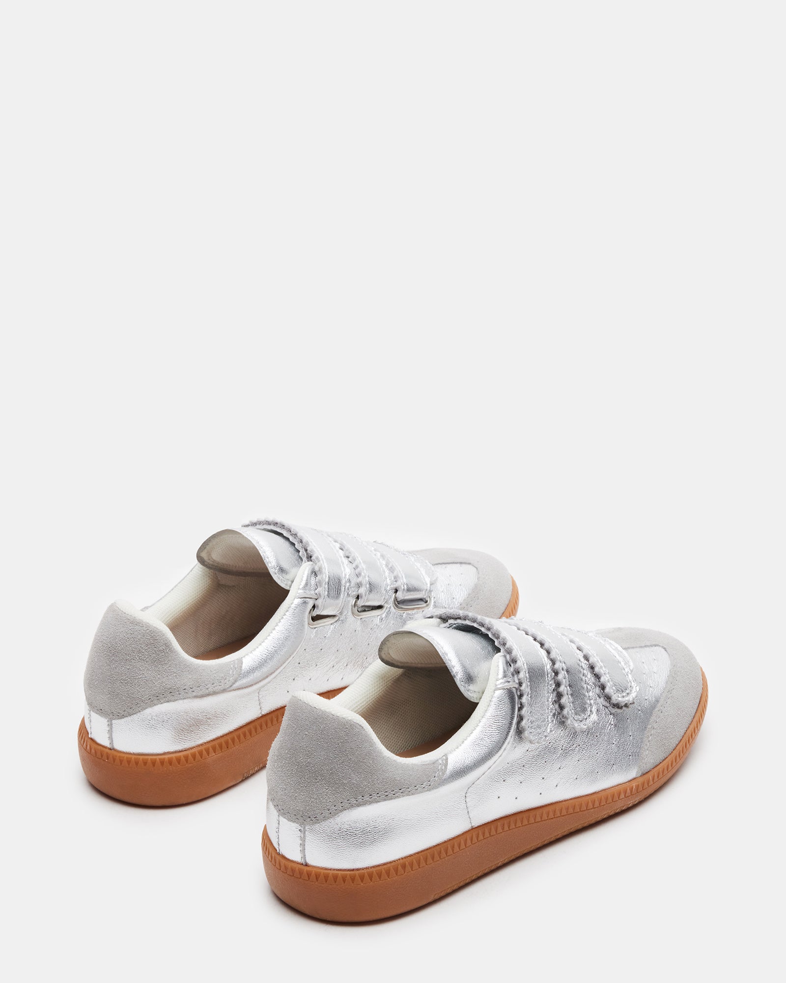 Lifestyle shot of man wearing mens white leather sneakers while walking through city park