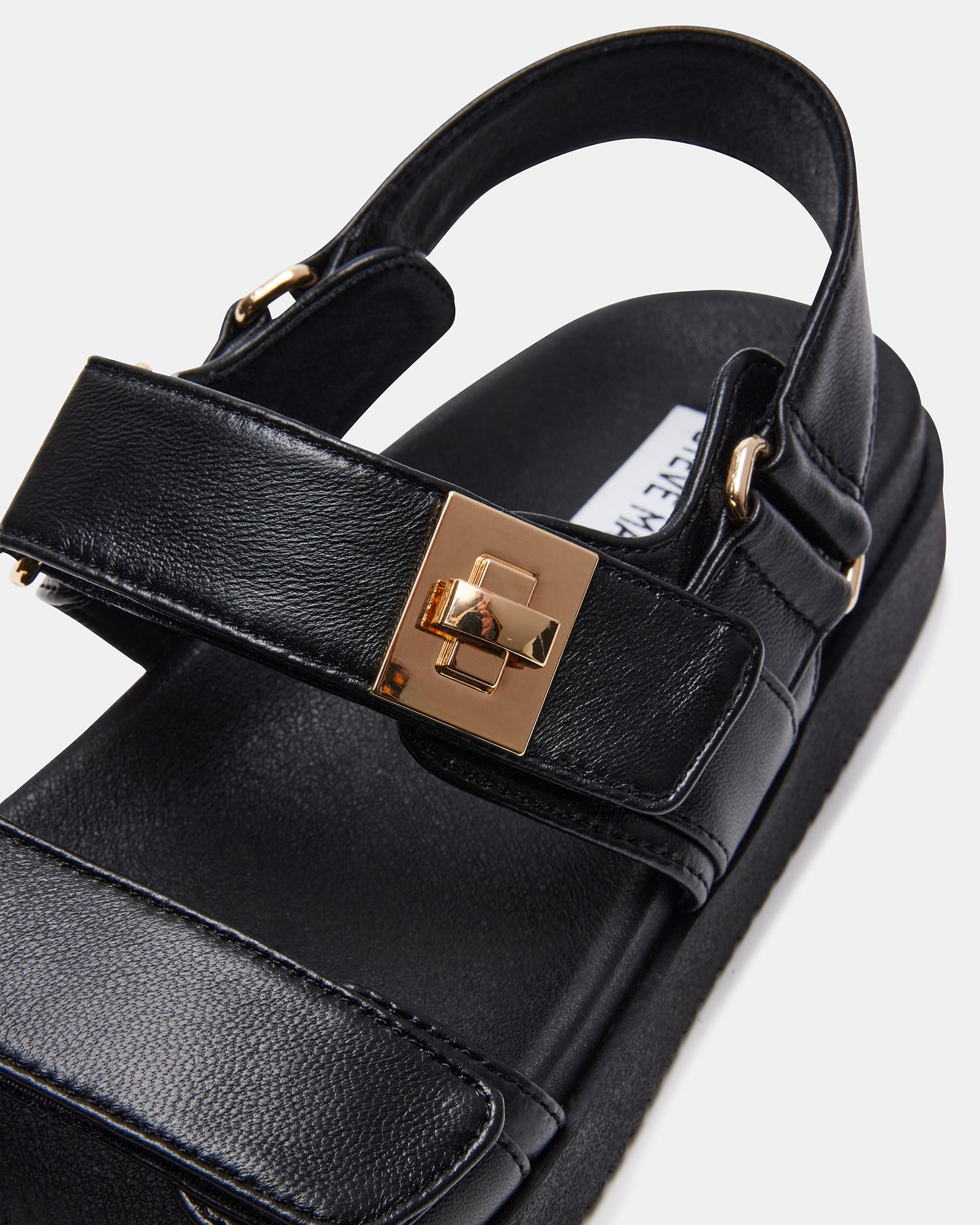 Top view of black flat sandals with molded footbed and gold hardware