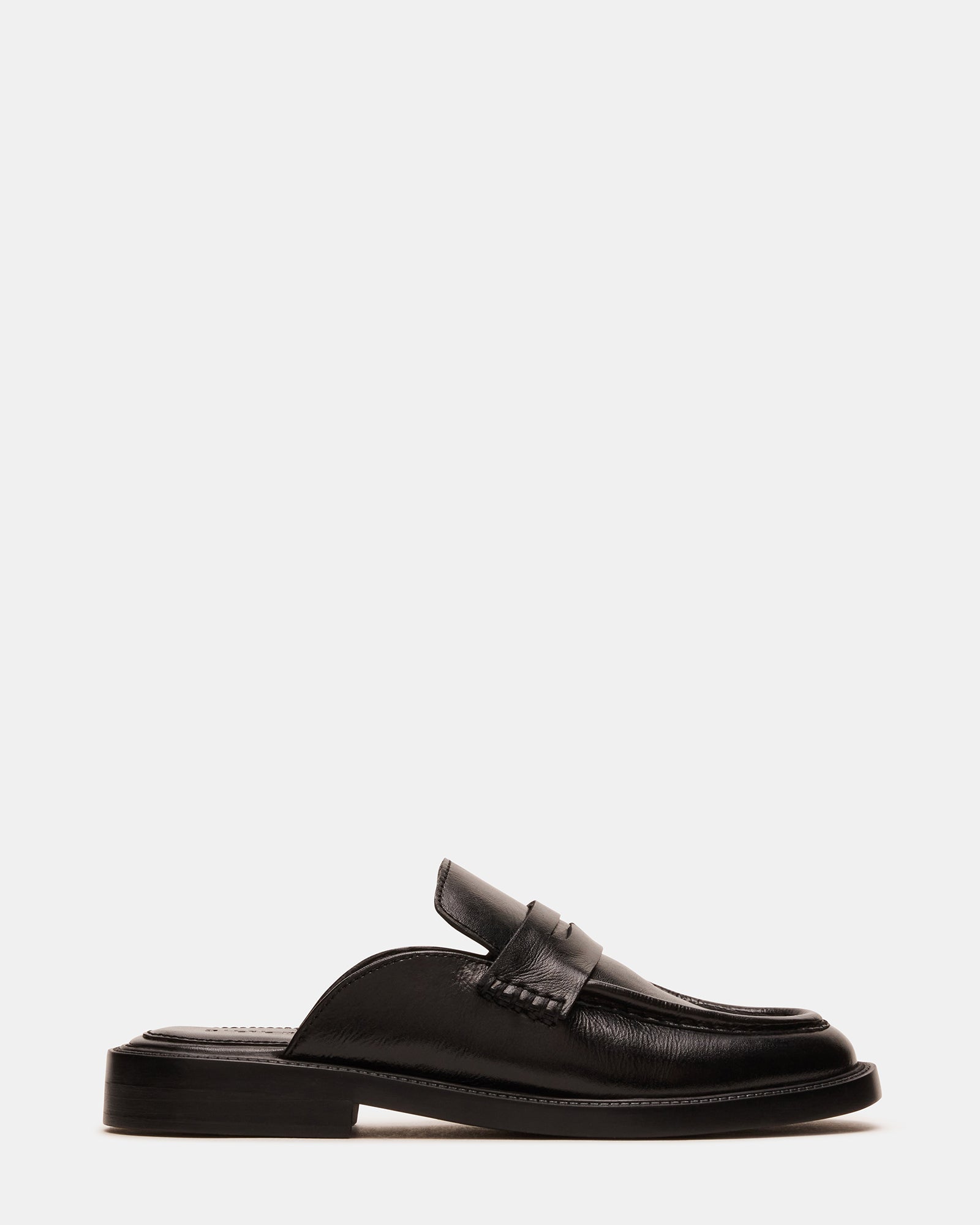 Front angle of black leather flat mules against marble backdrop