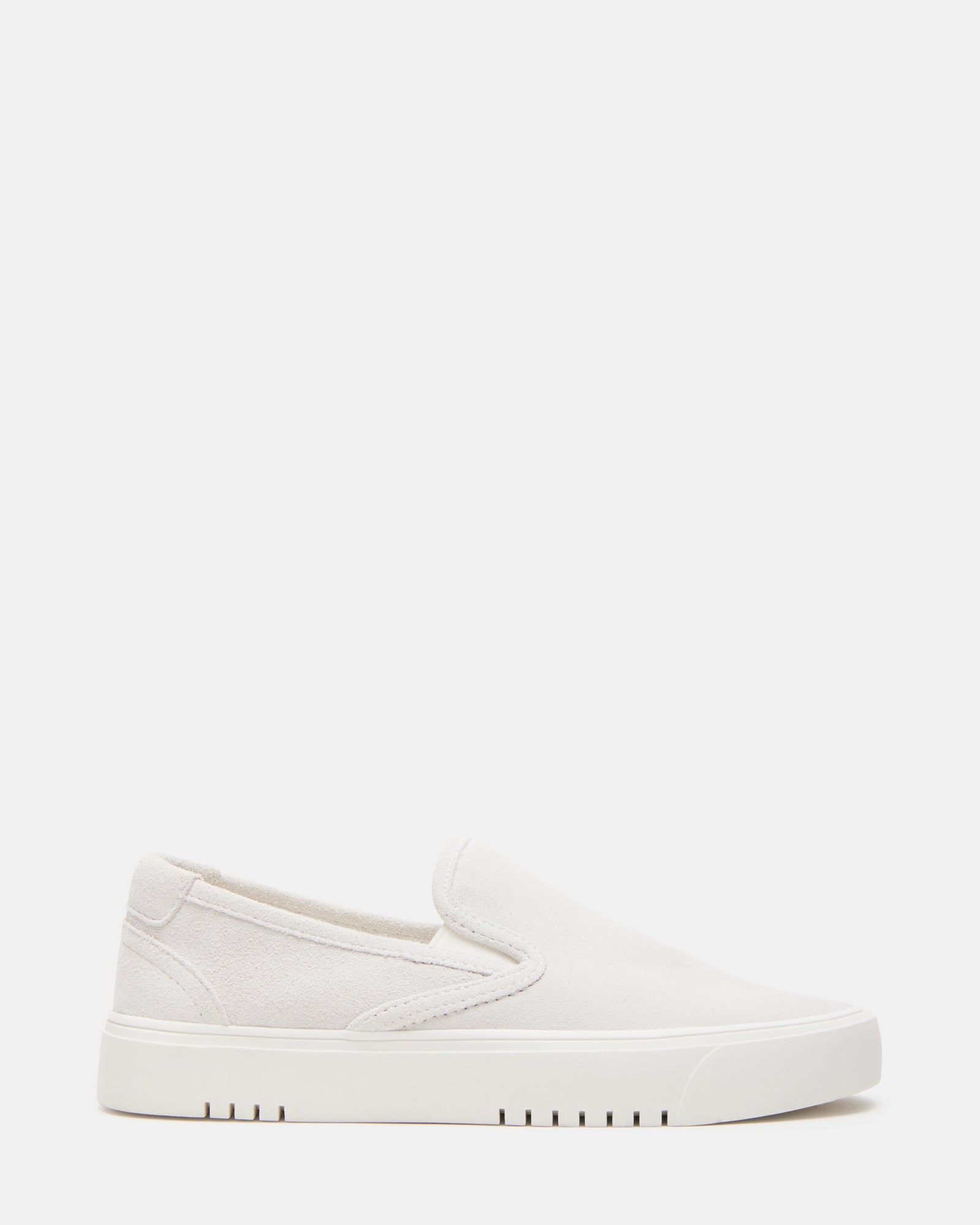 Side view of low-top sneakers in white suede worn with cuffed jeans
