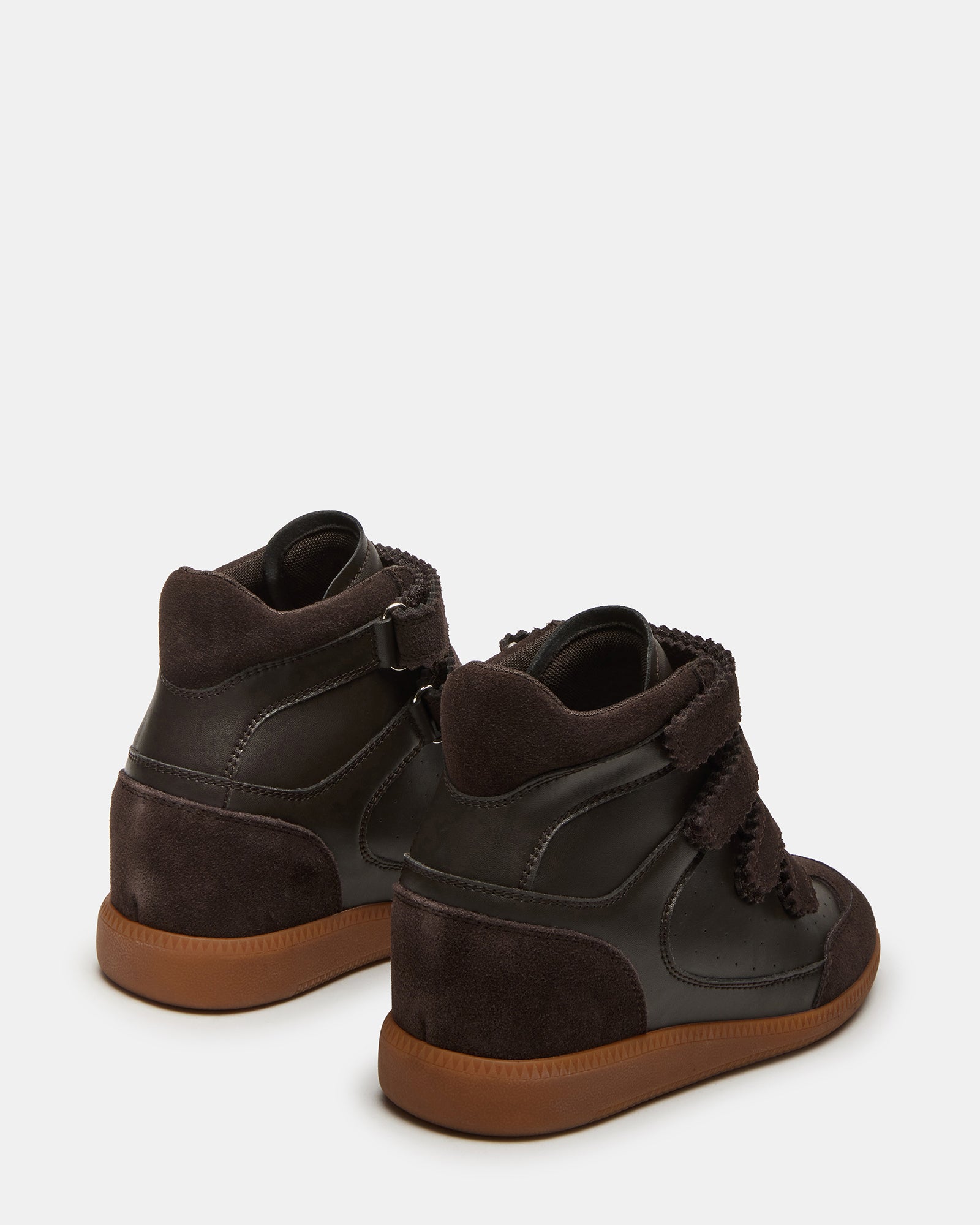 Side view of high-top sneakers with hidden wedge on a city street