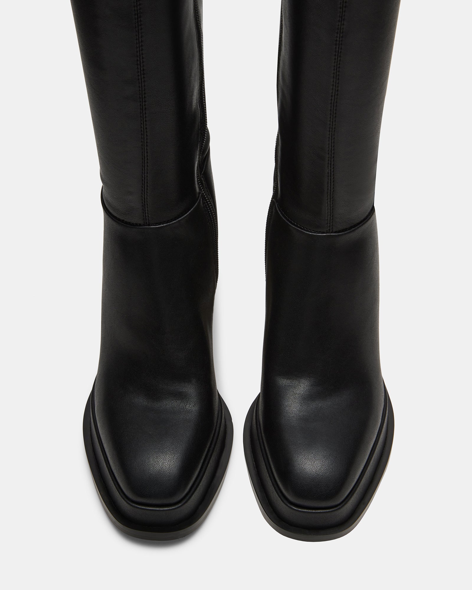 Side view of Myndie Black knee-high platform boots on a stylish backdrop.