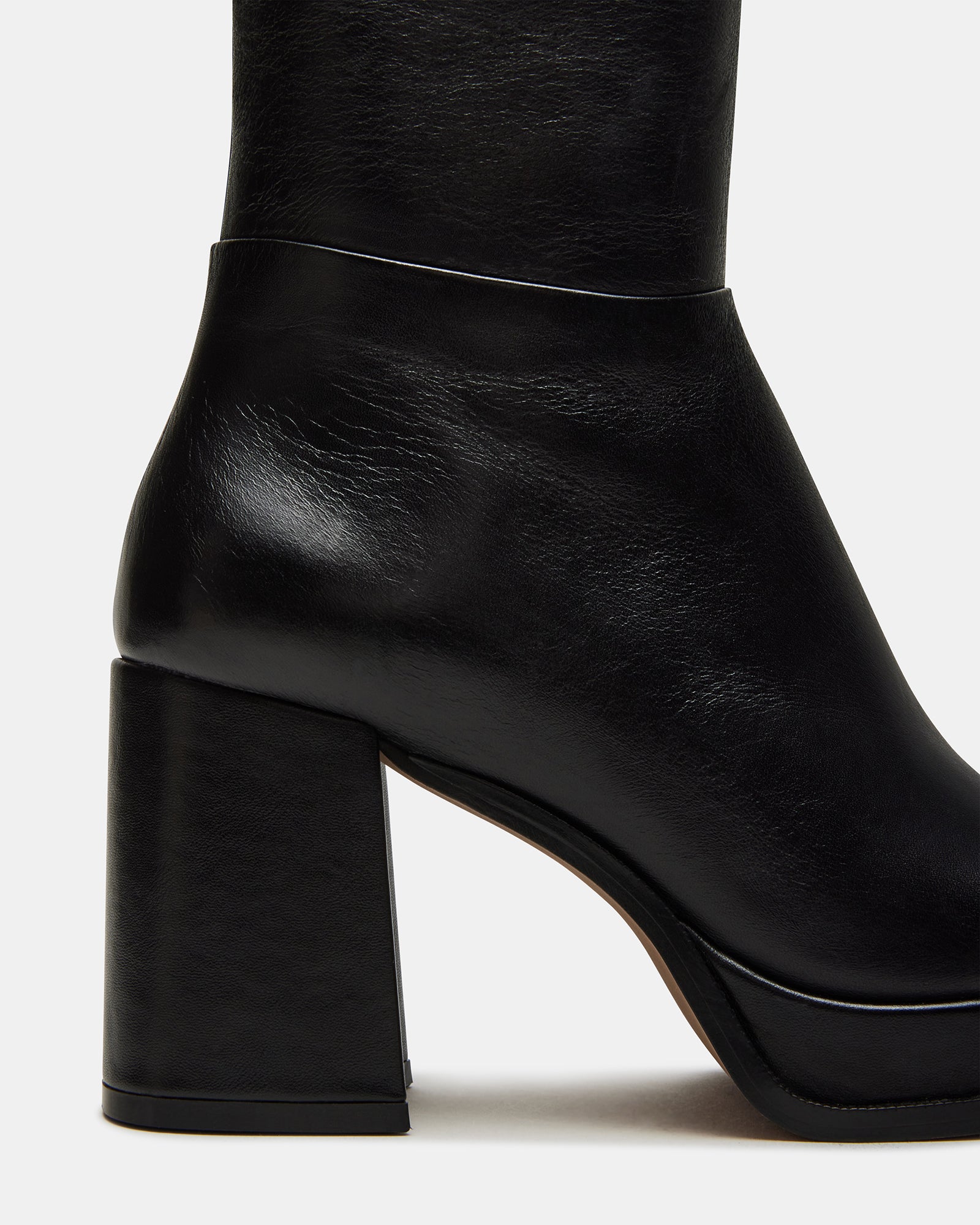 Black leather knee-high boots with square toe and platform heel on a models foot