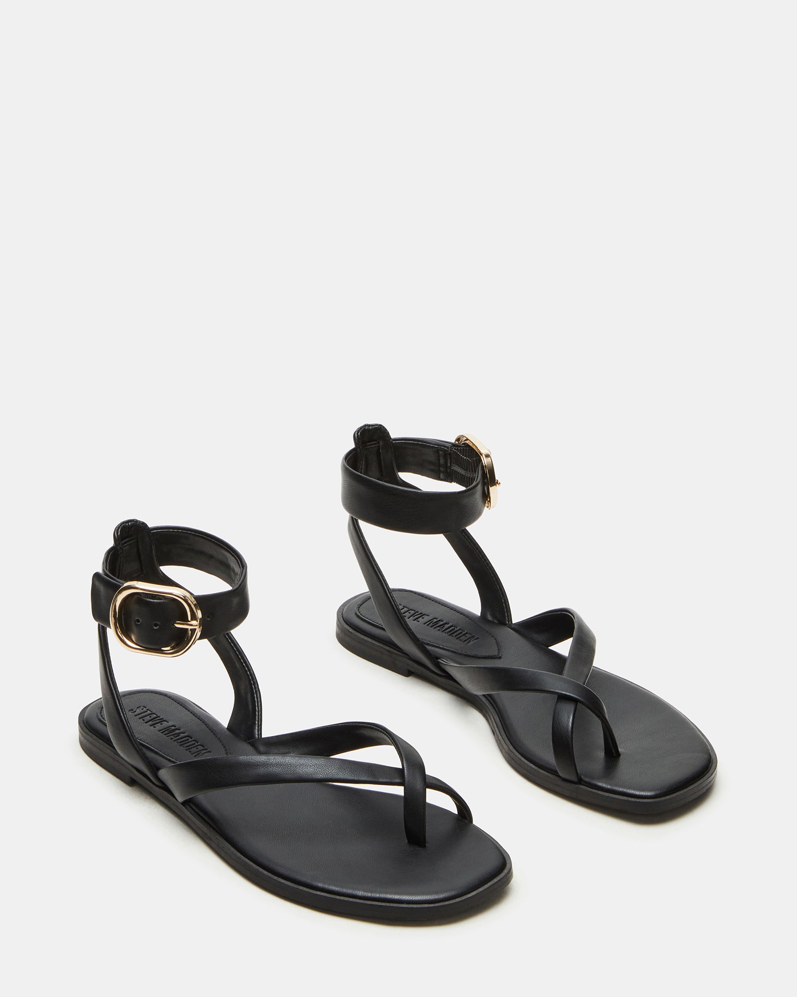 Model wearing black vegan leather flat sandals with ankle strap and casual outfit