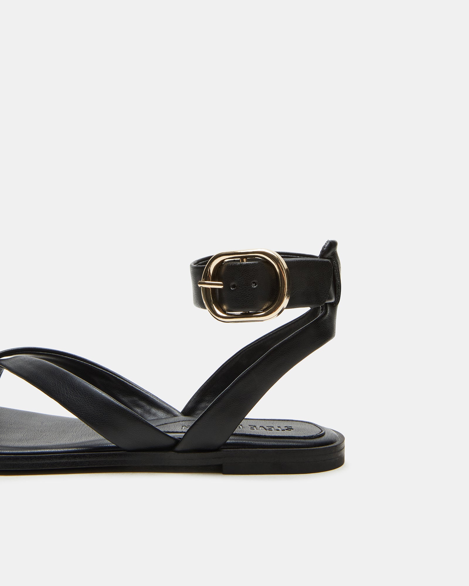 Close-up of black vegan leather flat sandals with ankle strap showing the strappy design