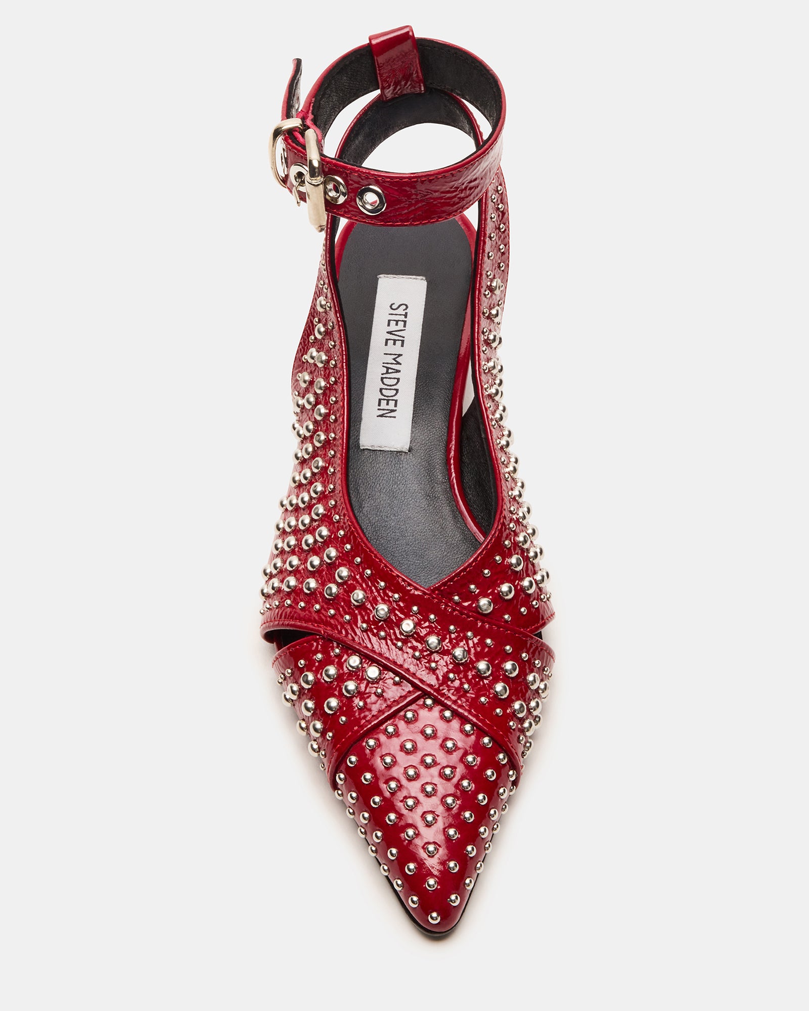 Close-up of red leather pointed toe slingback flats with stud embellishments on a wooden surface
