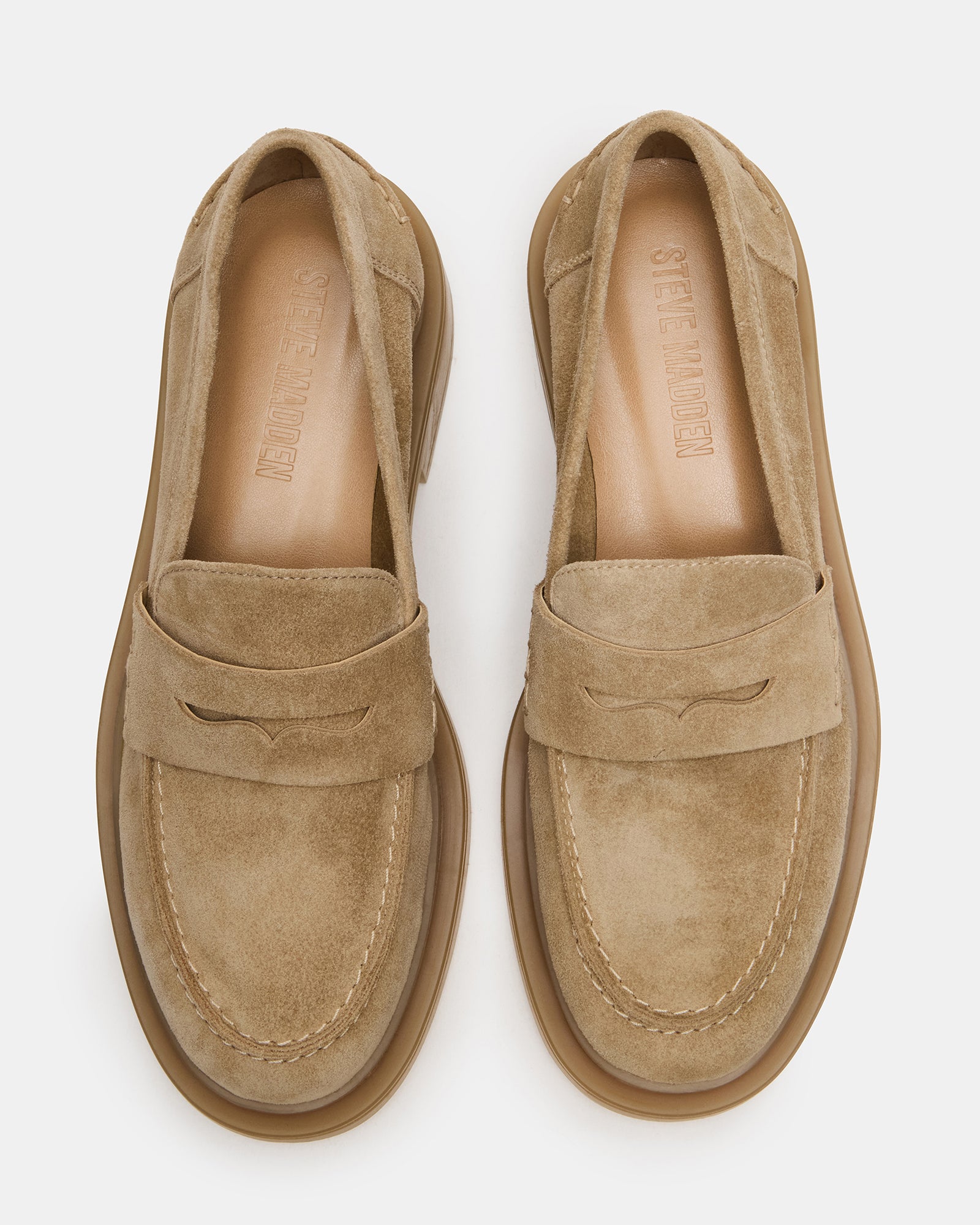 Mens taupe suede loafers with rounded toe and slip-on style on a wooden floor