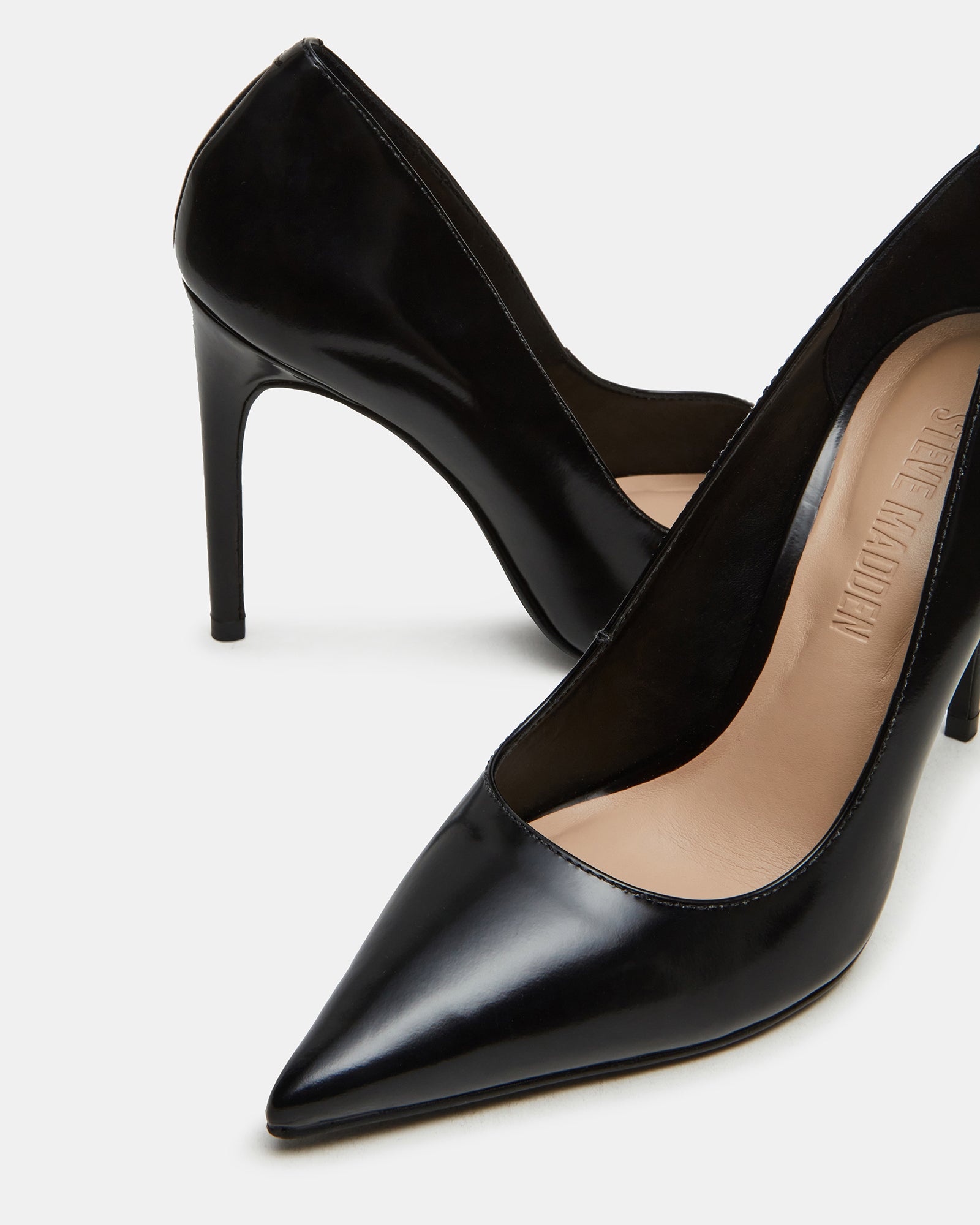 Black leather pointed toe pumps with stiletto heels on a models feet
