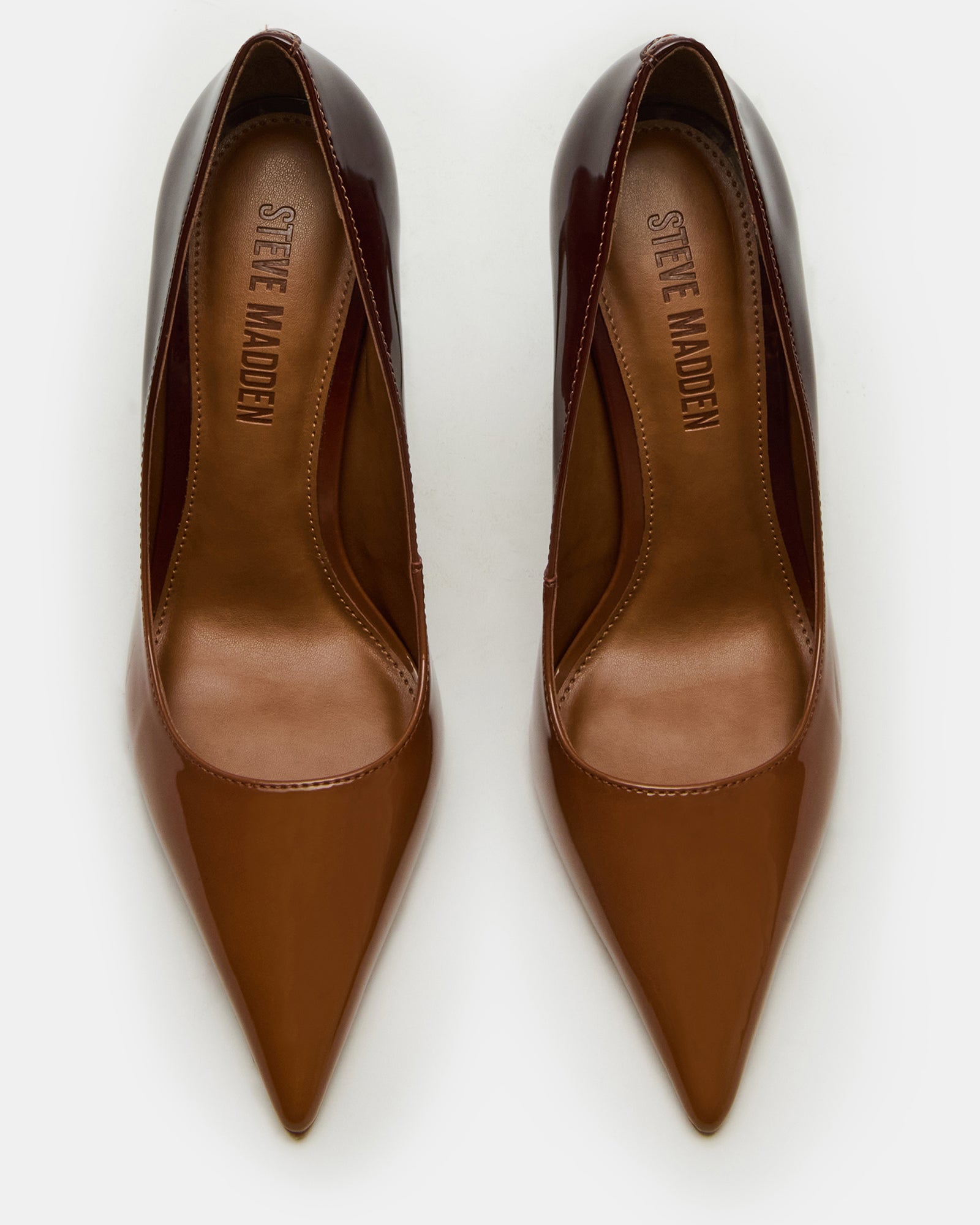 Angled close-up of black pointed toe heels on hardwood flooring