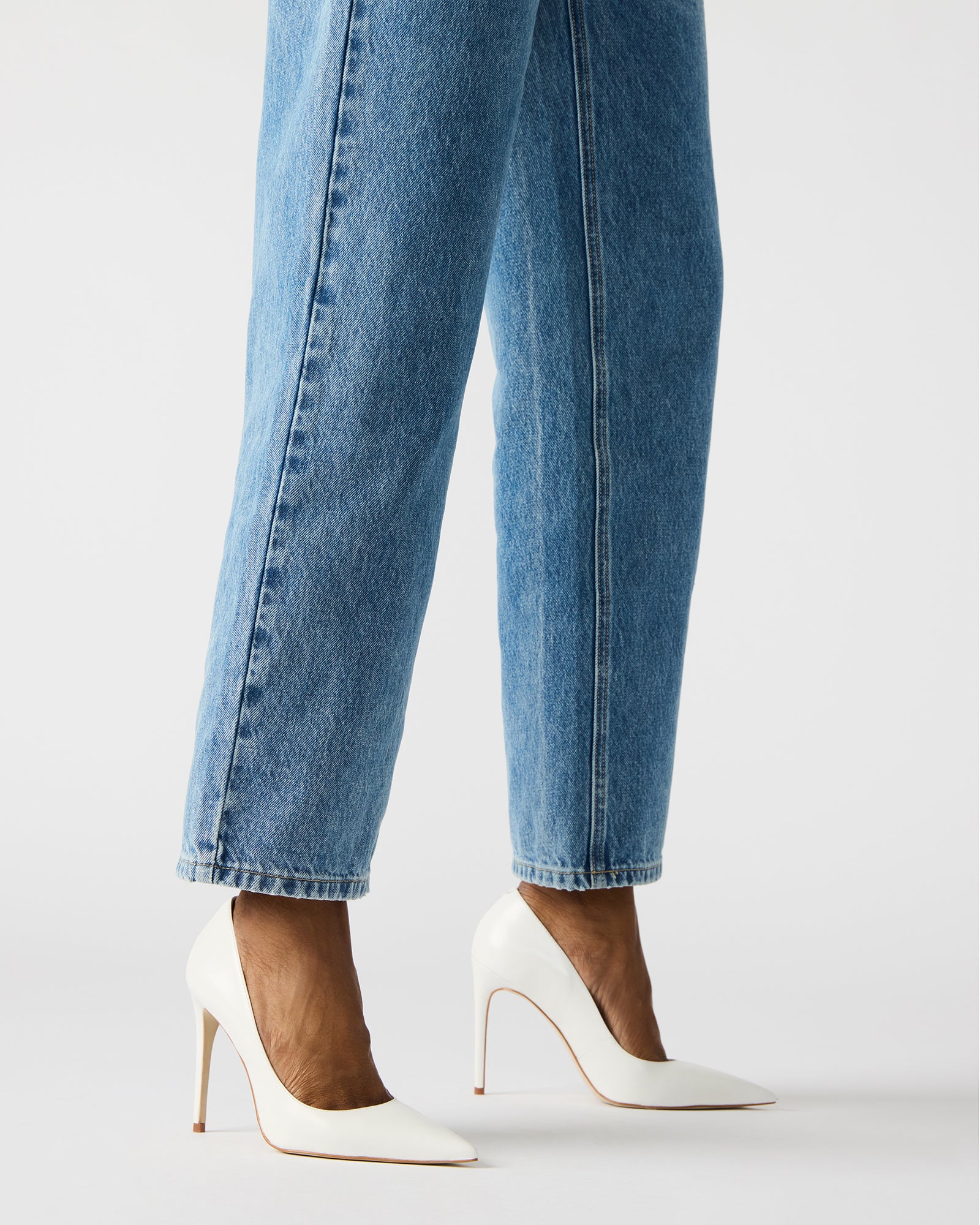 Close-up of white patent leather pumps highlighting luxurious texture.