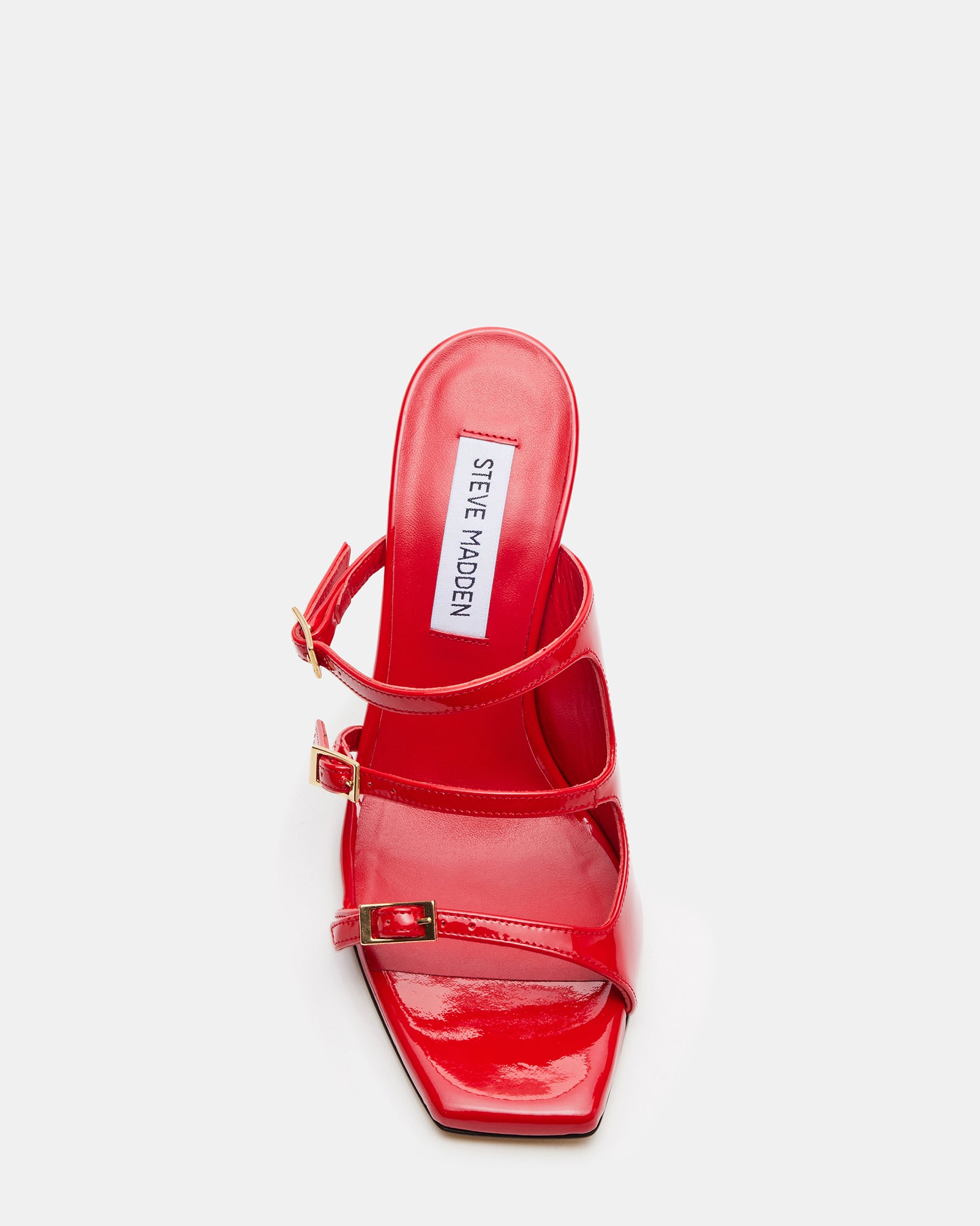 Opulent red patent leather high heels – side view on marble floor