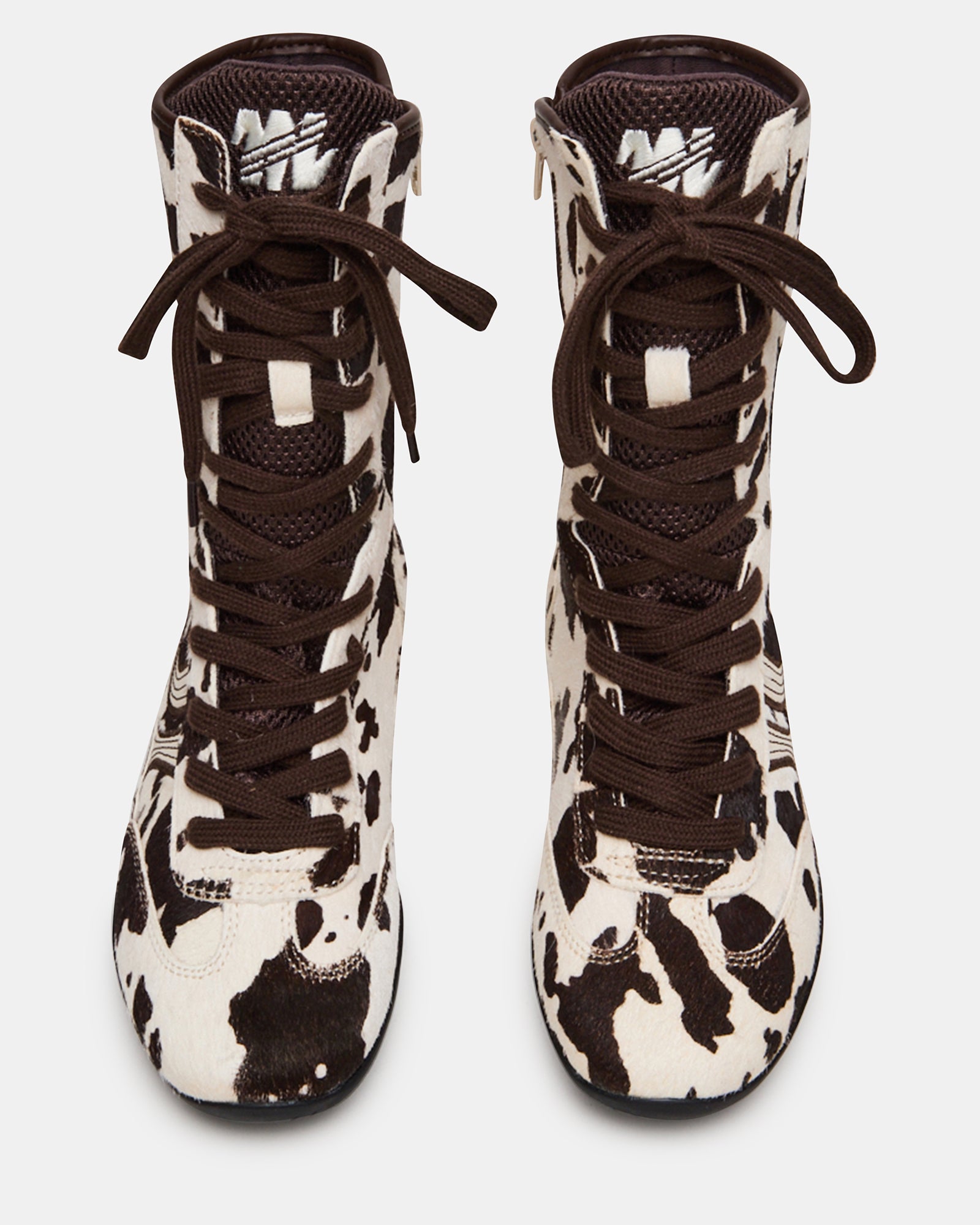 Side view of PAXTIN cow print high-top sneakers on a casual outfit.
