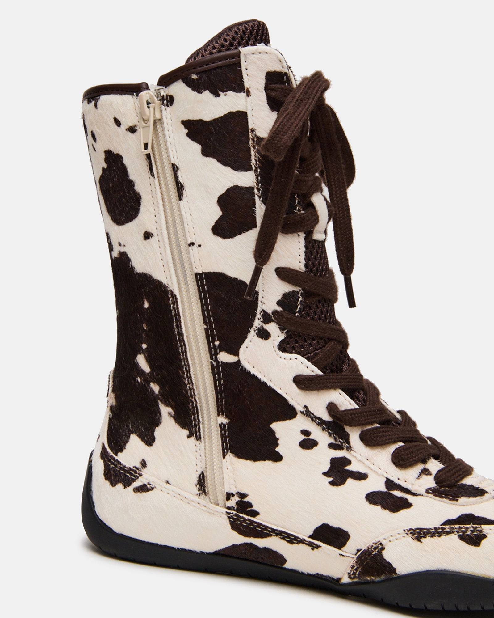 PAXTIN cow print high-top sneakers worn during an outdoor outing.