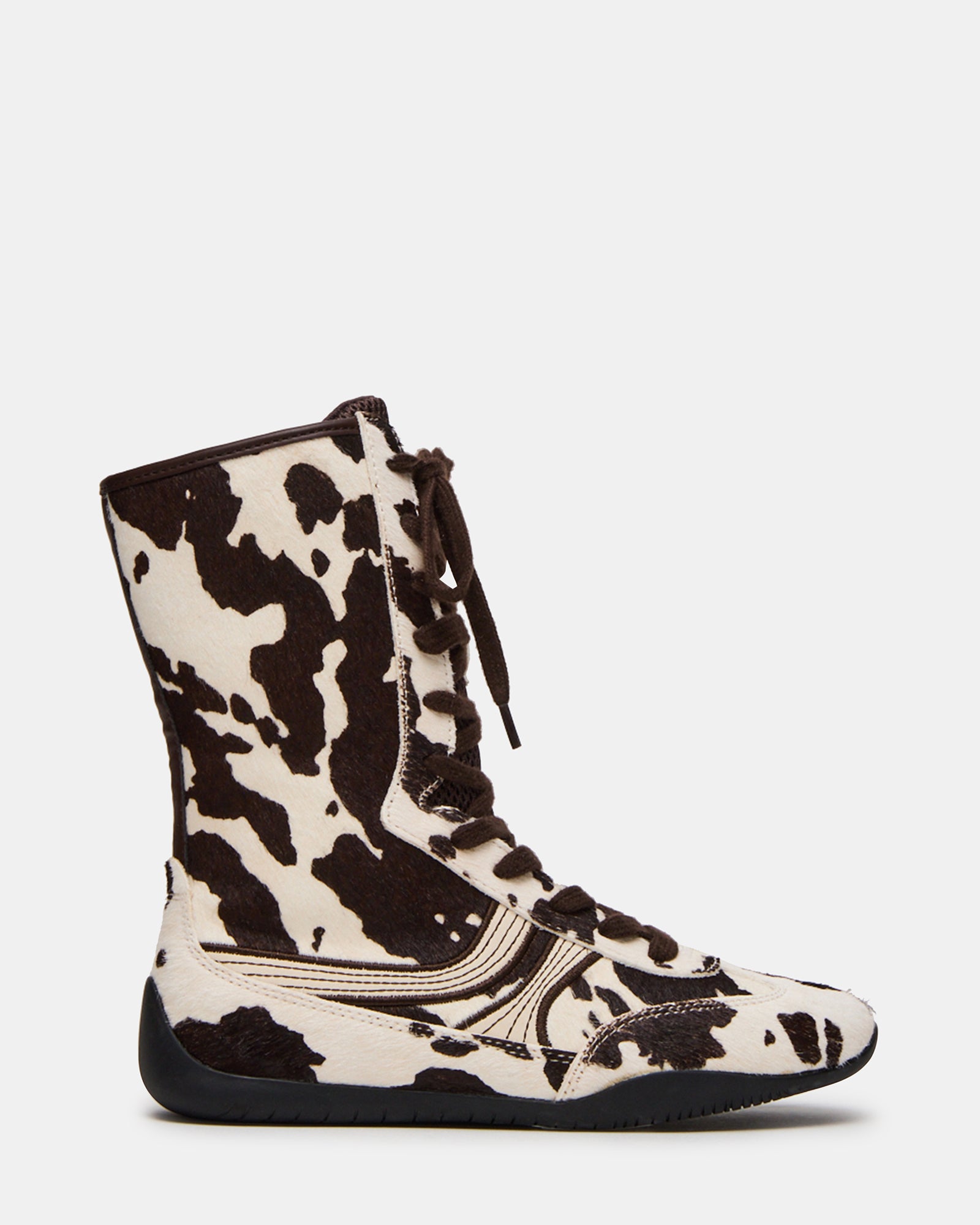 Side view of PAXTIN cow print high-top sneakers on a casual outfit.