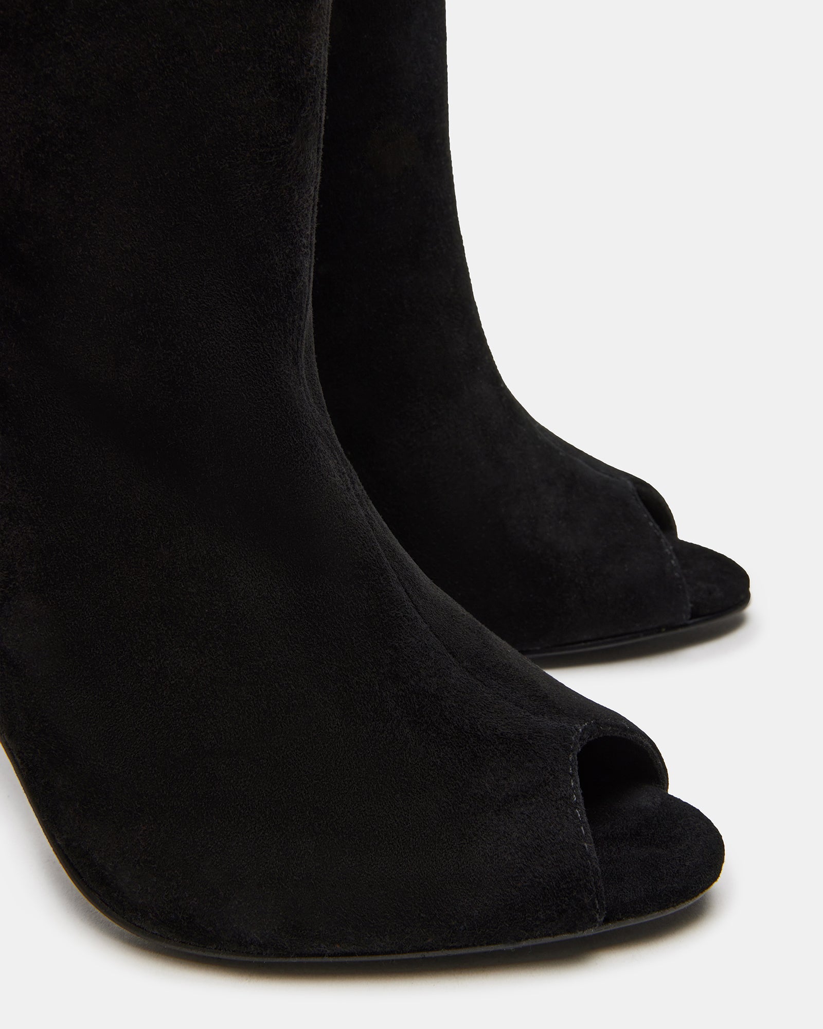 Close-up of red stiletto heels on black suede ankle boots