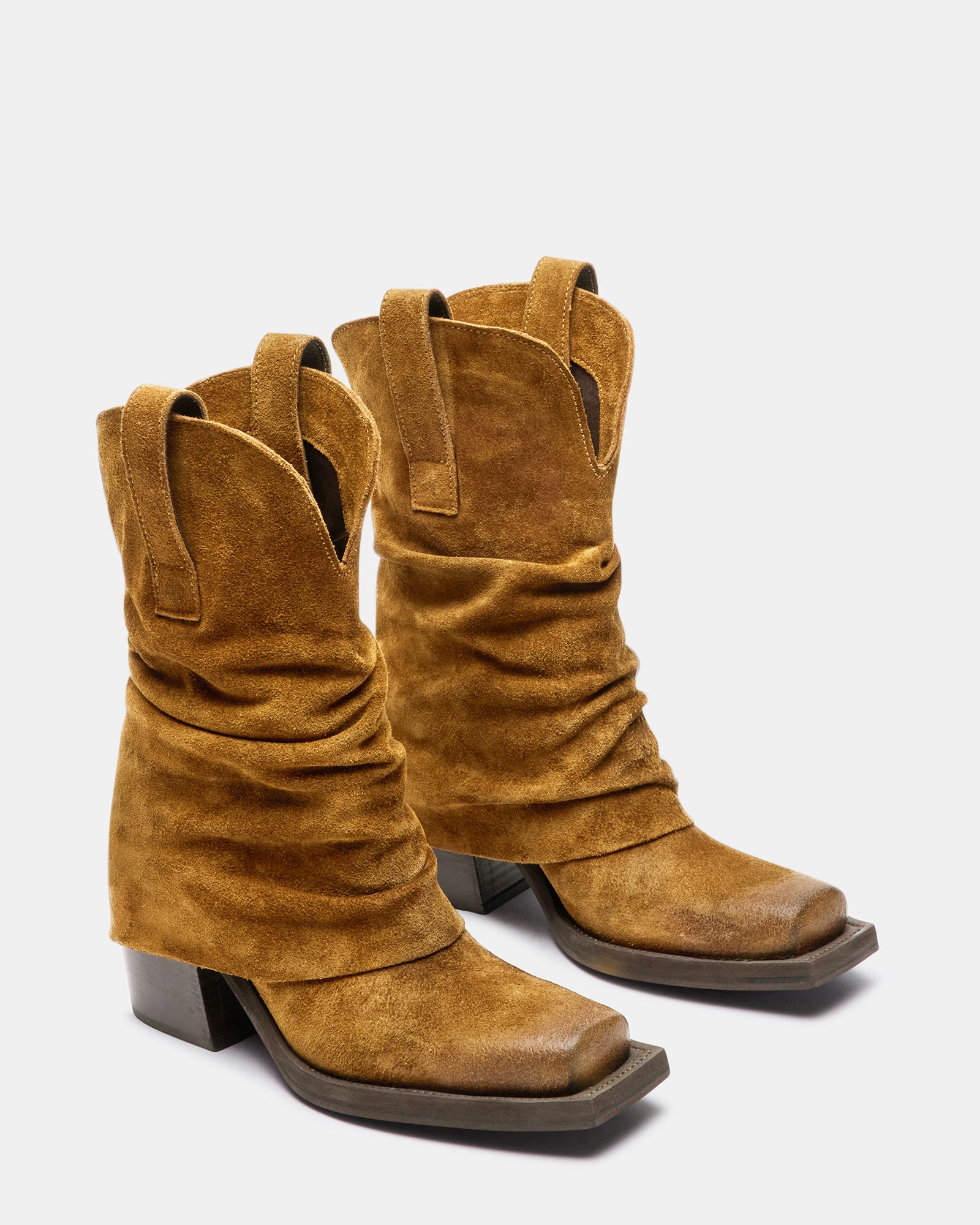 Side view of brown suede knee high boots on a model in an outdoor setting.