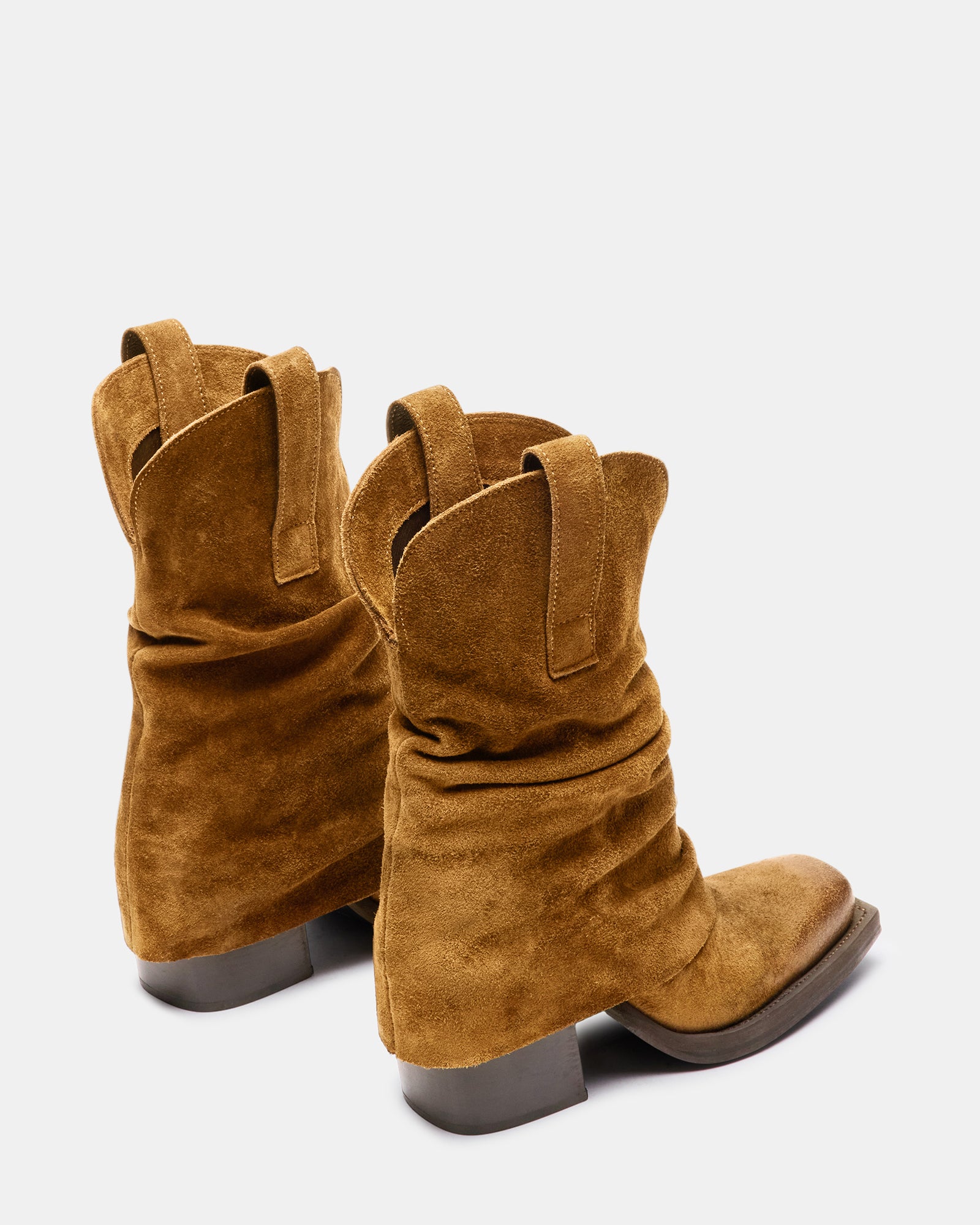 Side view of brown suede knee high boots on a model in an outdoor setting.