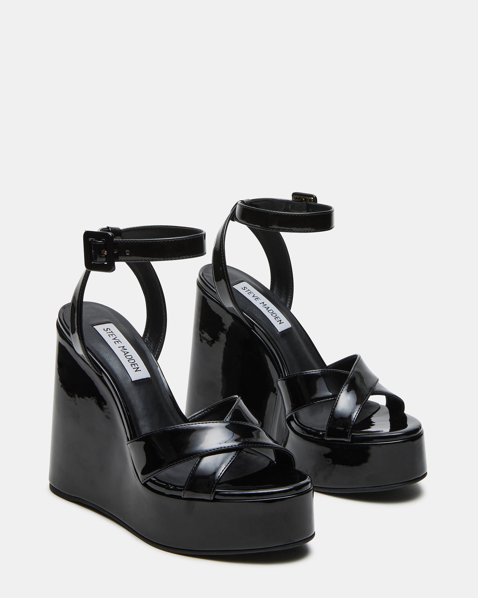 Model wearing Pinnacle black patent platform wedges for a chic look suitable for parties or casual outings