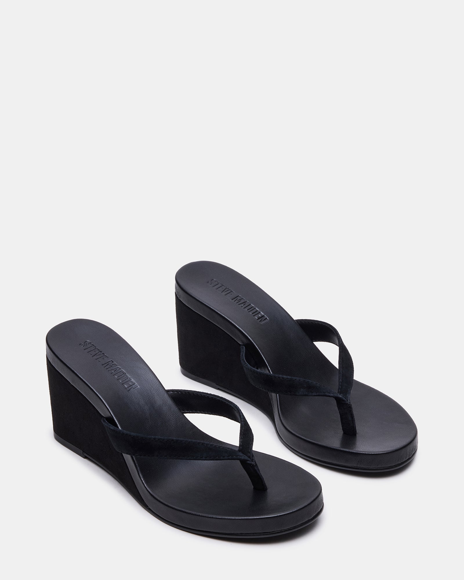 Model wearing black suede wedge sandals in a summer outdoor setting