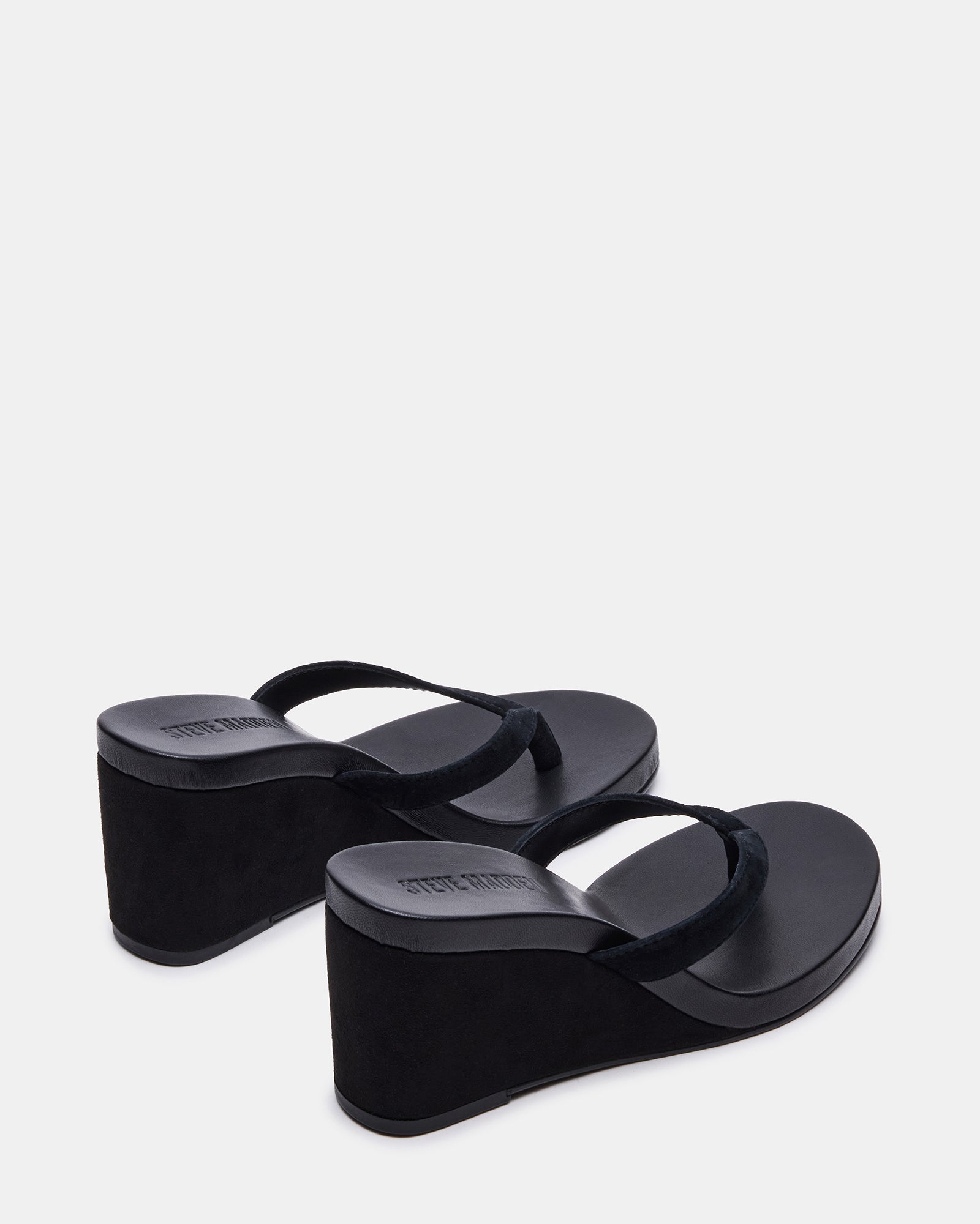 Model wearing black suede wedge sandals in a summer outdoor setting