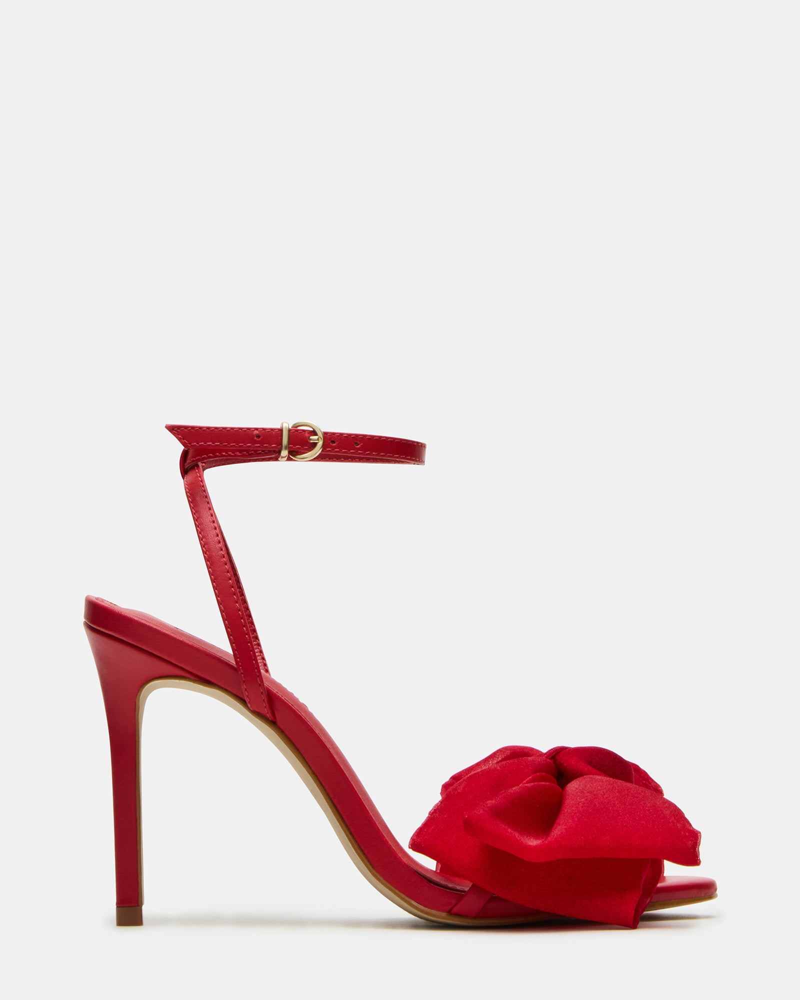 Close-up of red strappy heels with bow detailing on glossy surface