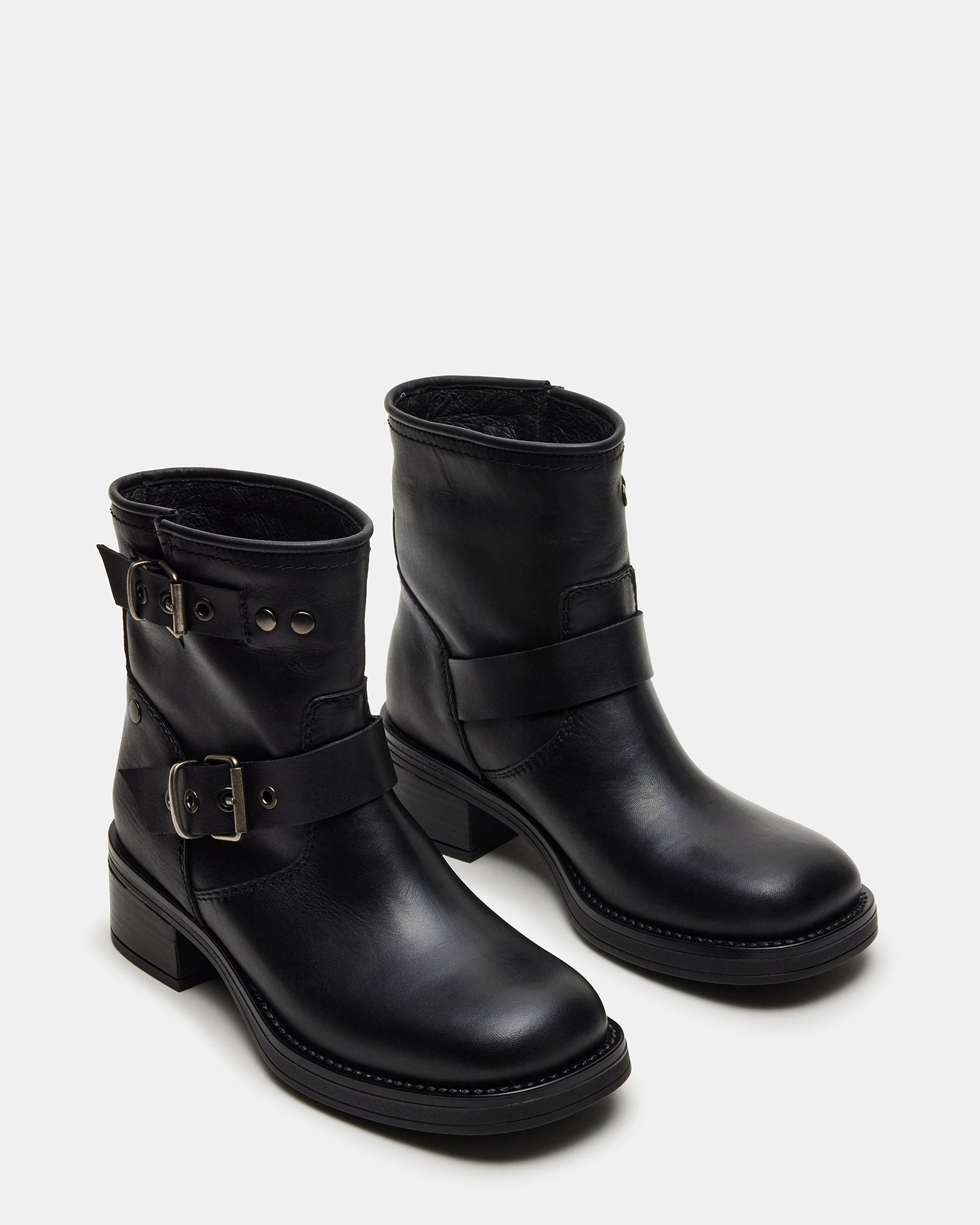 Close-up of black leather boots on concrete, highlighting lugged sole grip