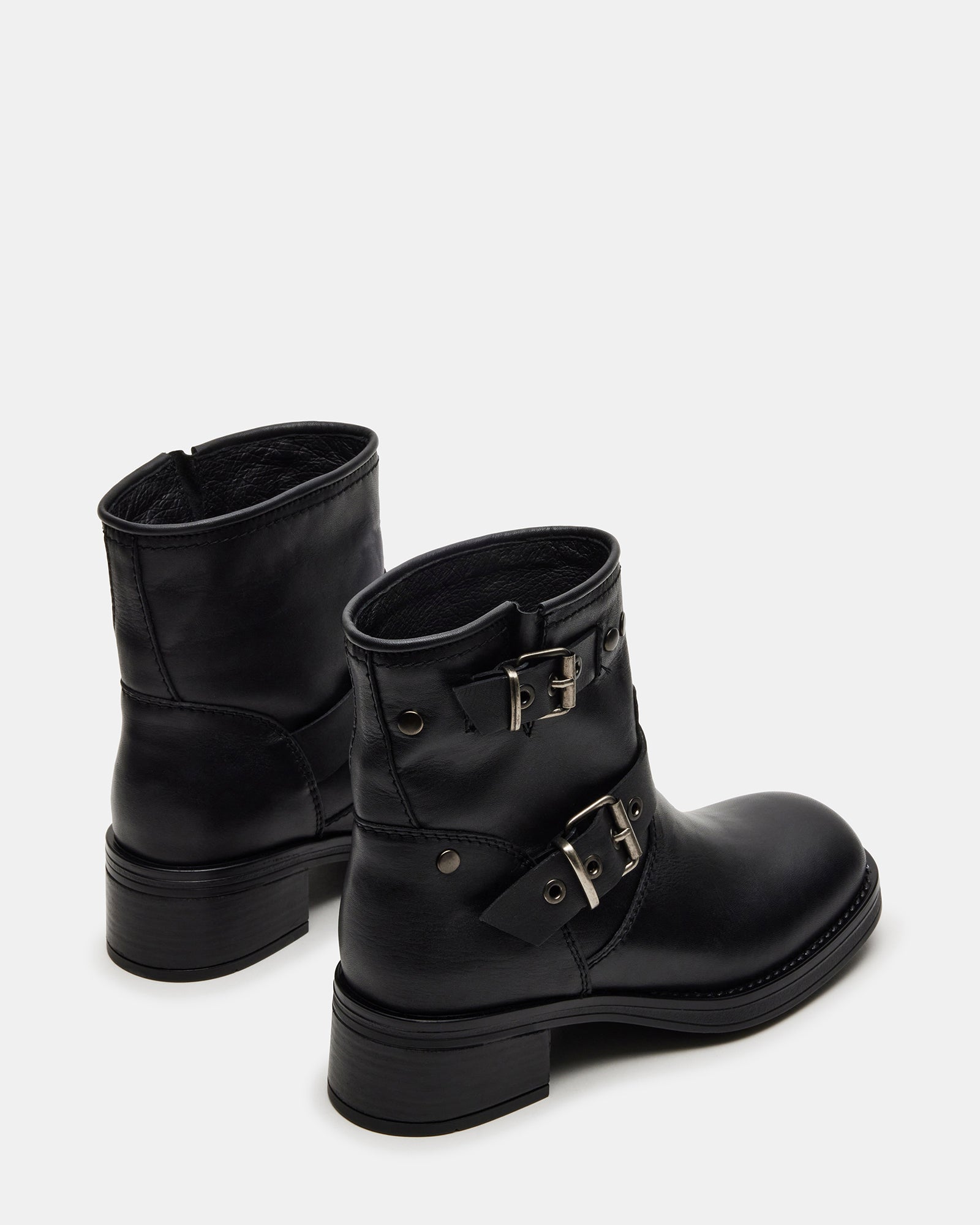 Close-up of black leather boots on concrete, highlighting lugged sole grip