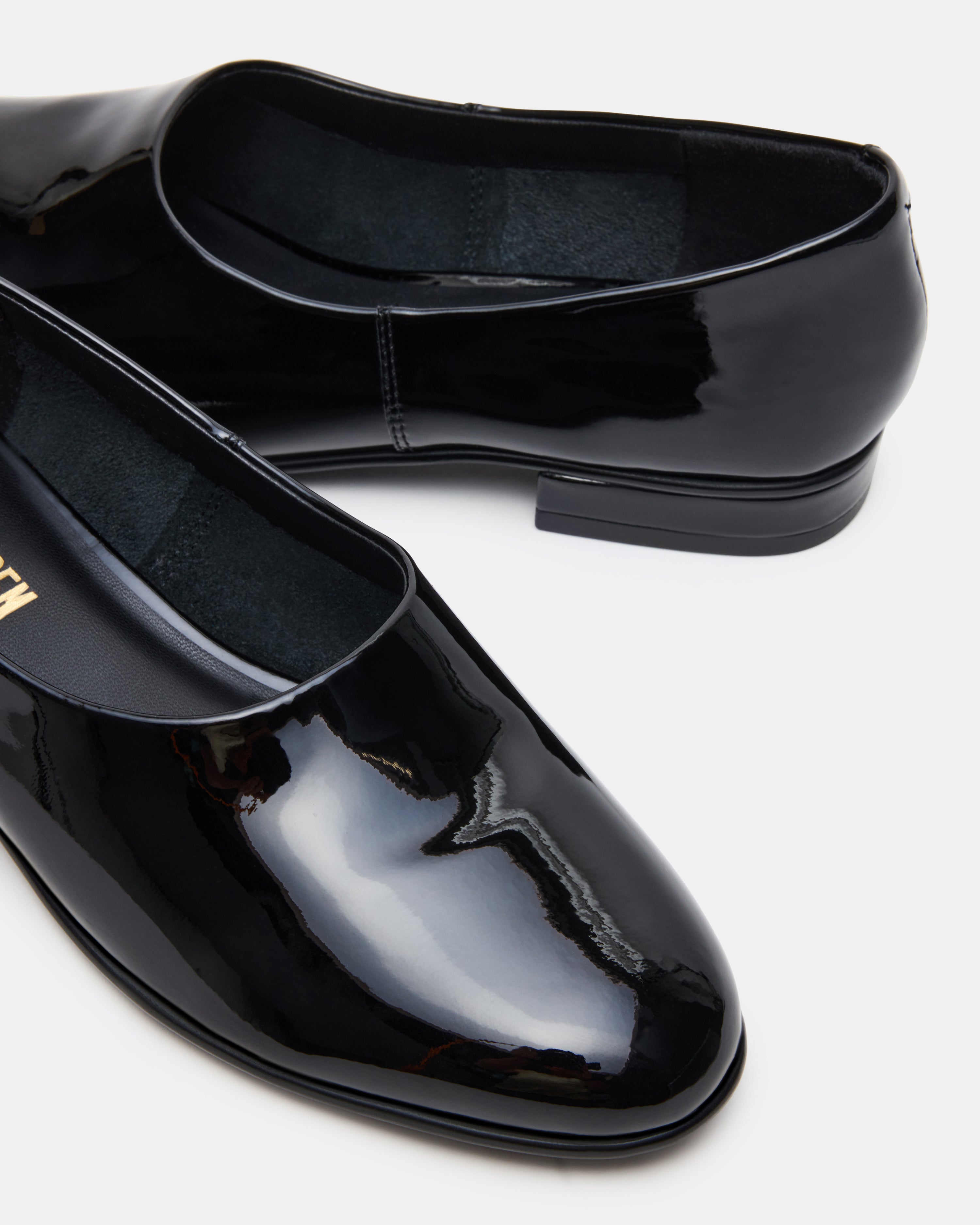 Woman walking in black patent flats on city sidewalk
