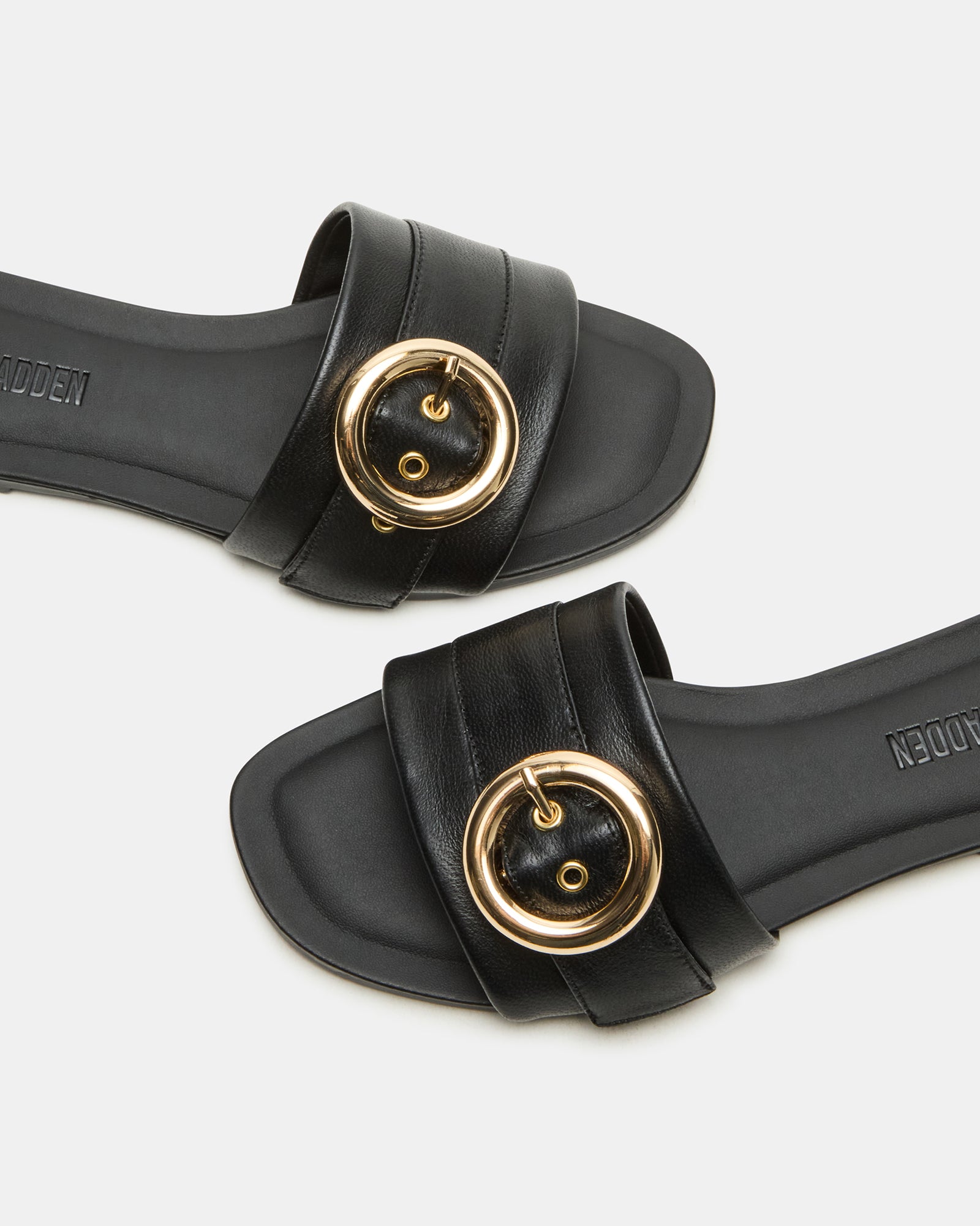 Side angle of black leather slide sandals showing the square toe and buckle detail.
