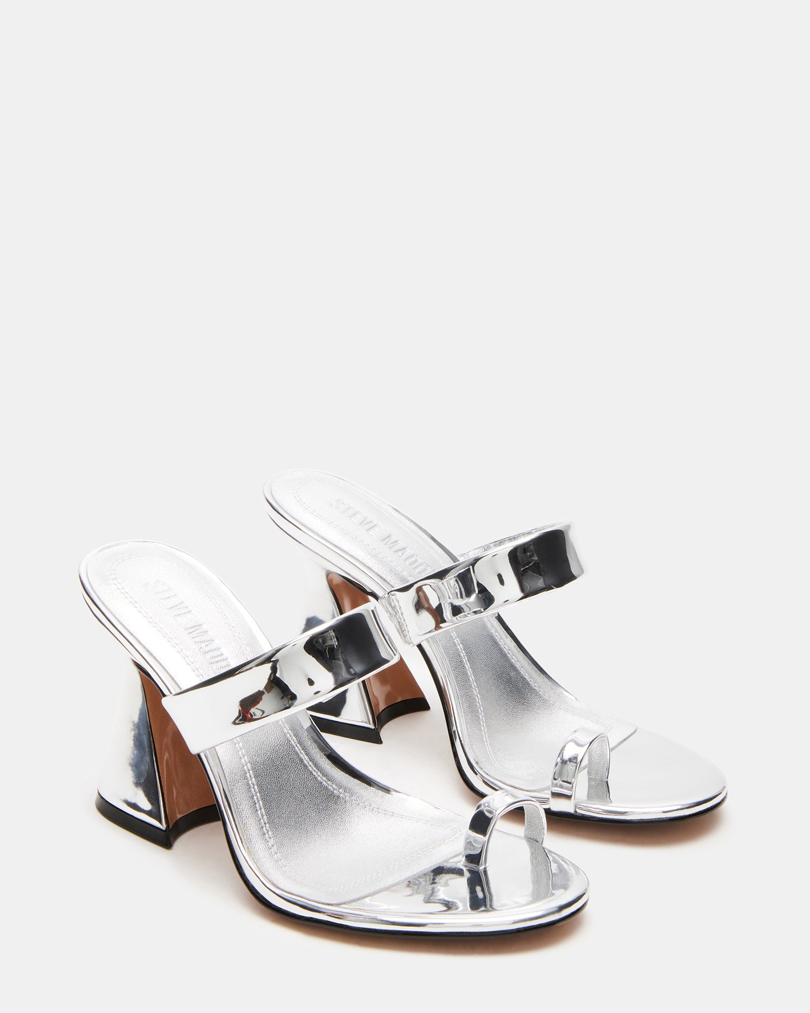 Side profile highlighting angular heel of kitten heel mules on a hardwood floor