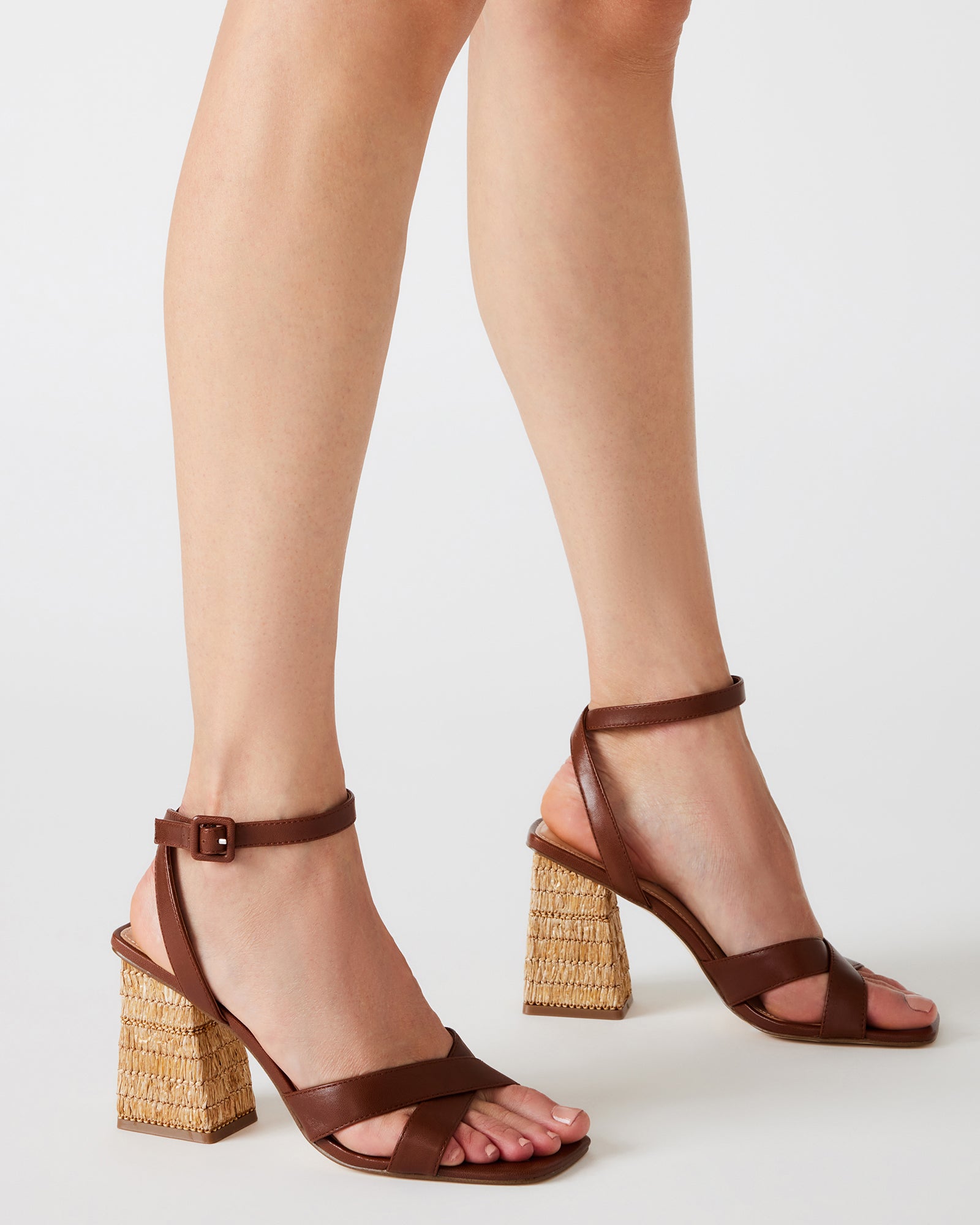 Close-up of the criss-cross straps on brown leather sandals.